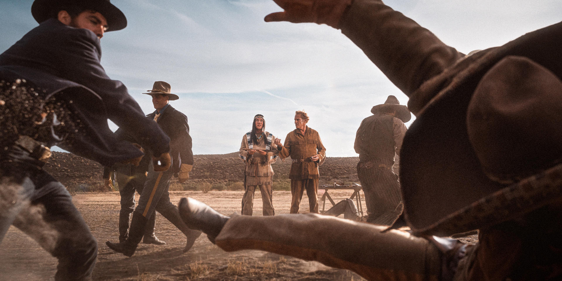 Szene zeigt ein Wild-West-Duell. Figuren in historischer Kleidung stehen sich in einer Wüstenlandschaft gegenüber. Intensives, dramatisches Licht.