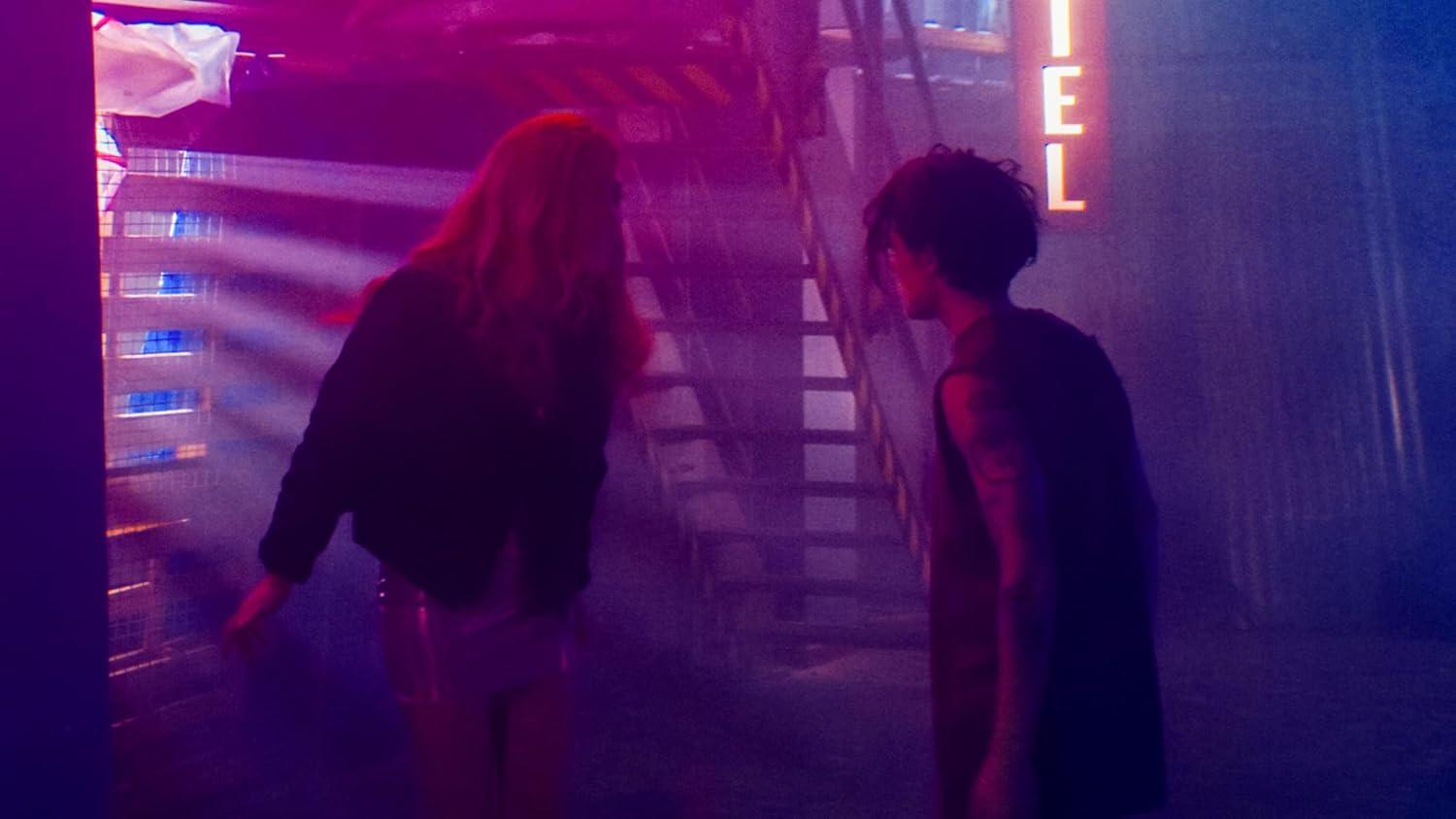 Zwei Personen stehen in der Nähe einer Treppe und einem 'TEL'-Schild. Die Szene hat ein Neon-, Lila- und Blau-Farbschema mit einer dunklen, stimmungsvollen Atmosphäre.