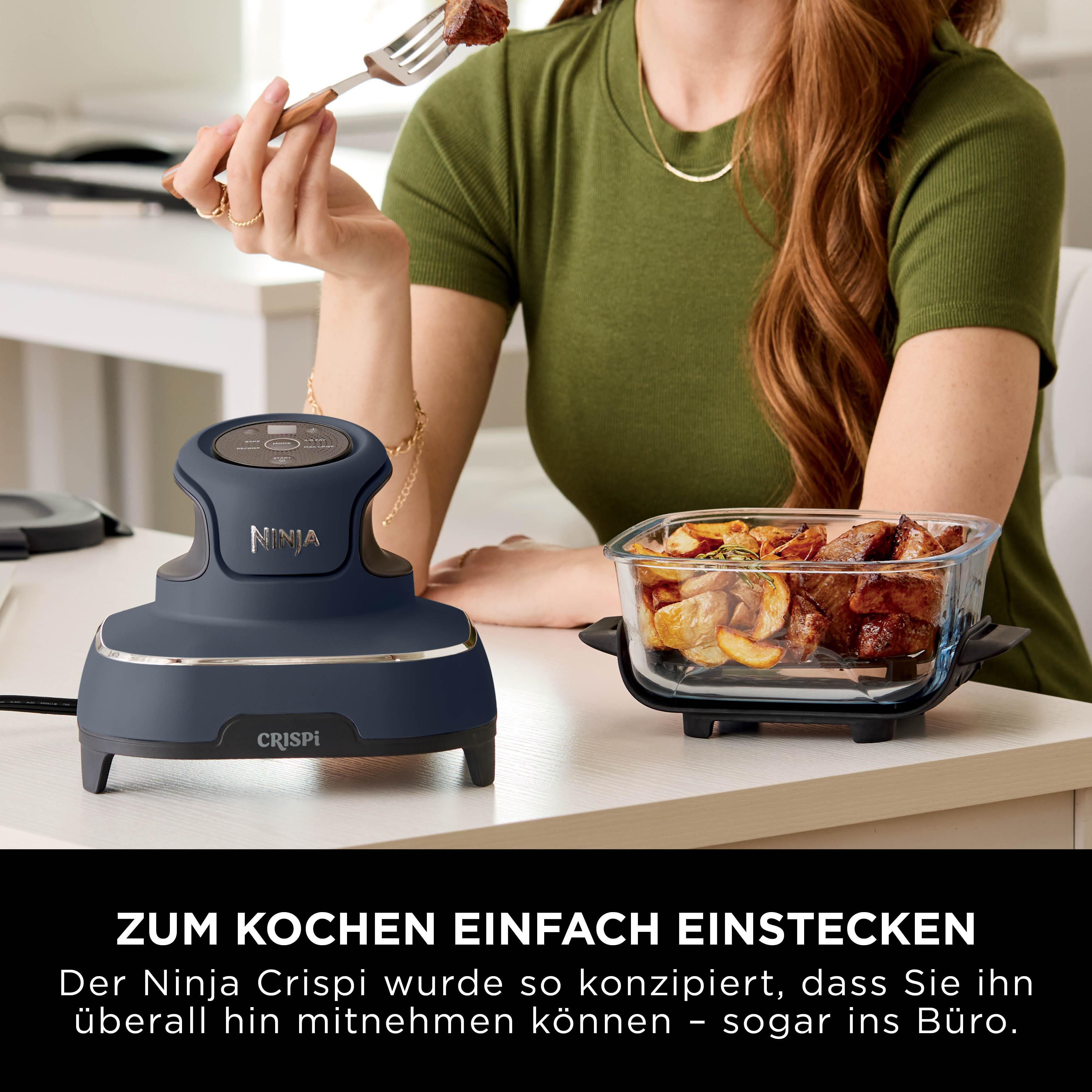 Eine Frau hält eine Gabel mit Essen in der Nähe eines Ninja Crispi. Ein Glasbehälter mit gekochtem Essen ist ebenfalls vorhanden.