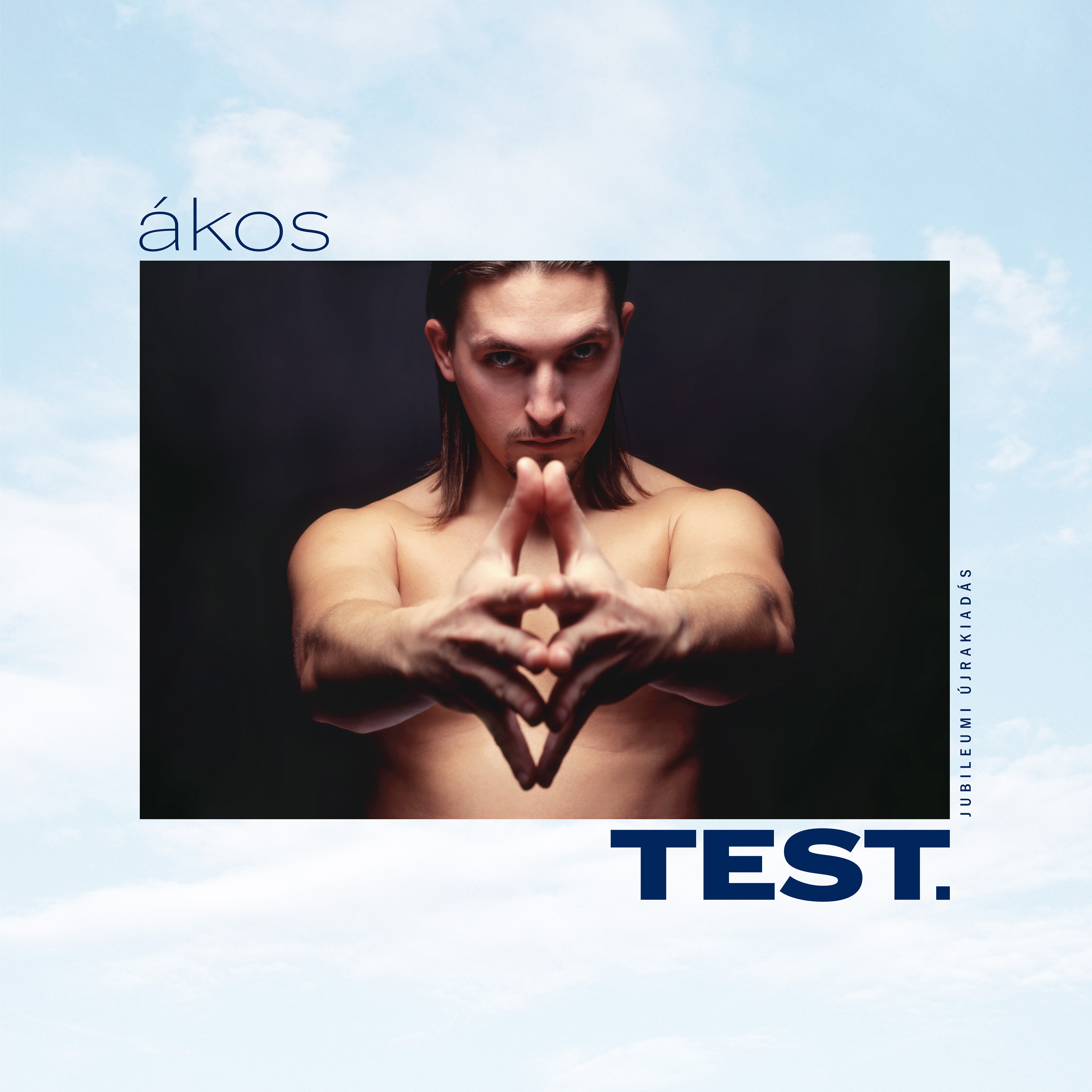 Egy férfi gyémánt formát alkot a kezével. A szöveg tartalmazza az 'ákos' és a 'TEST.' szavakat. A háttér kék ég.