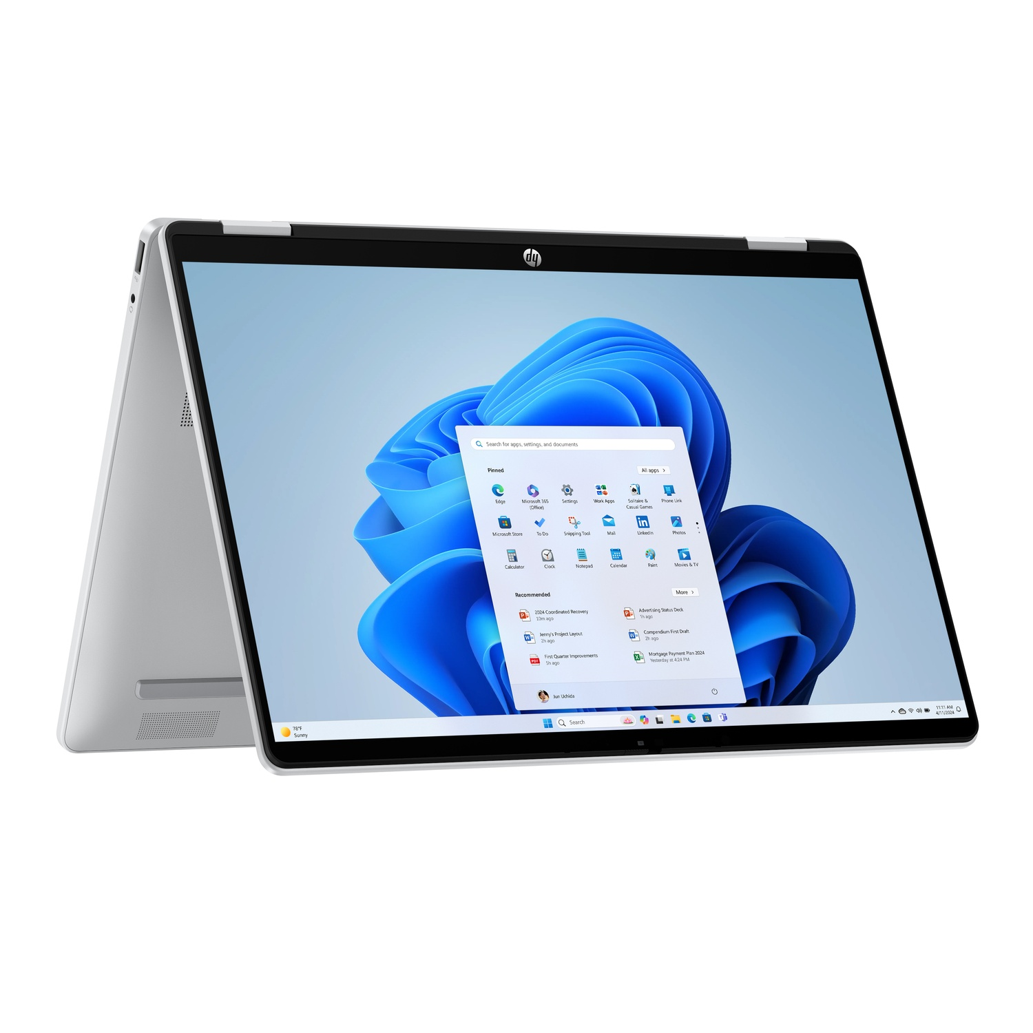 A silver HP laptop is open, displaying the Windows 11 interface. The screen shows the start menu, with various app icons and widgets.