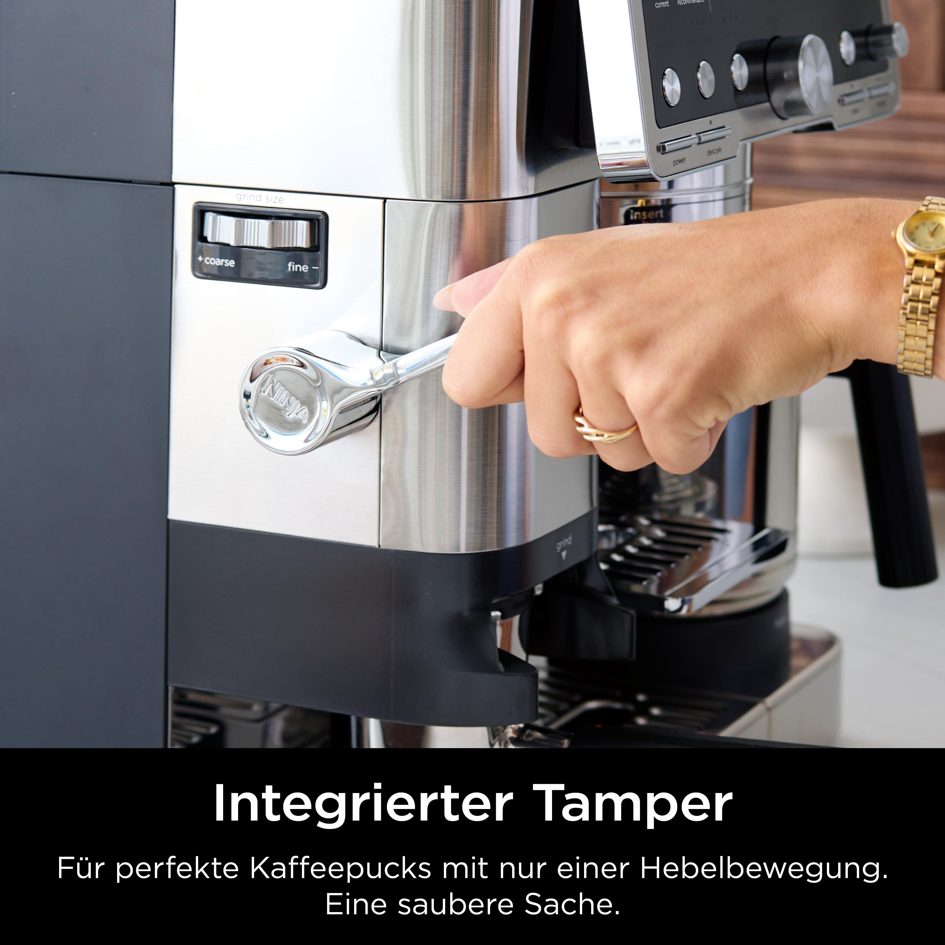 Die Hand einer Person bedient einen Hebel an einer Ninja-Kaffeemaschine. Die Maschine ist aus Edelstahl mit Schwarz-Weiß-Paneel.