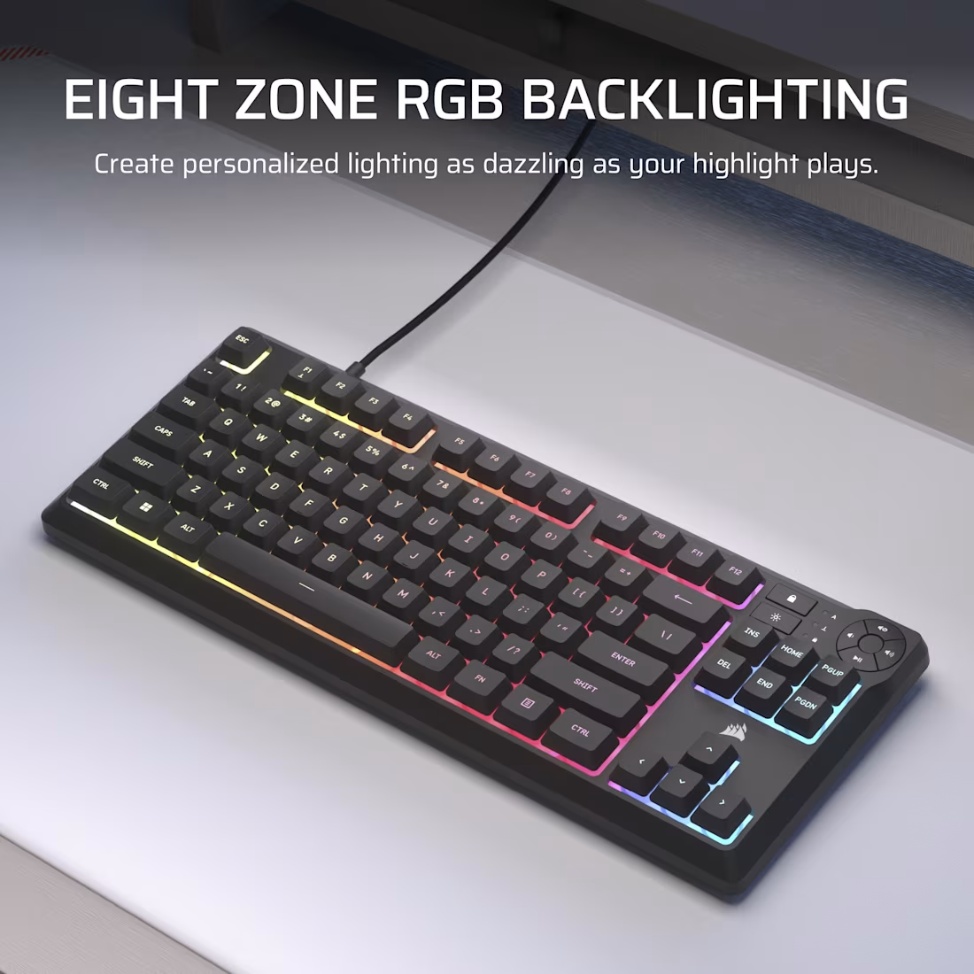 Clavier noir avec éclairage RGB. Les touches sont illuminées en couleurs arc-en-ciel. Le clavier est sur une surface blanche avec un câble noir.