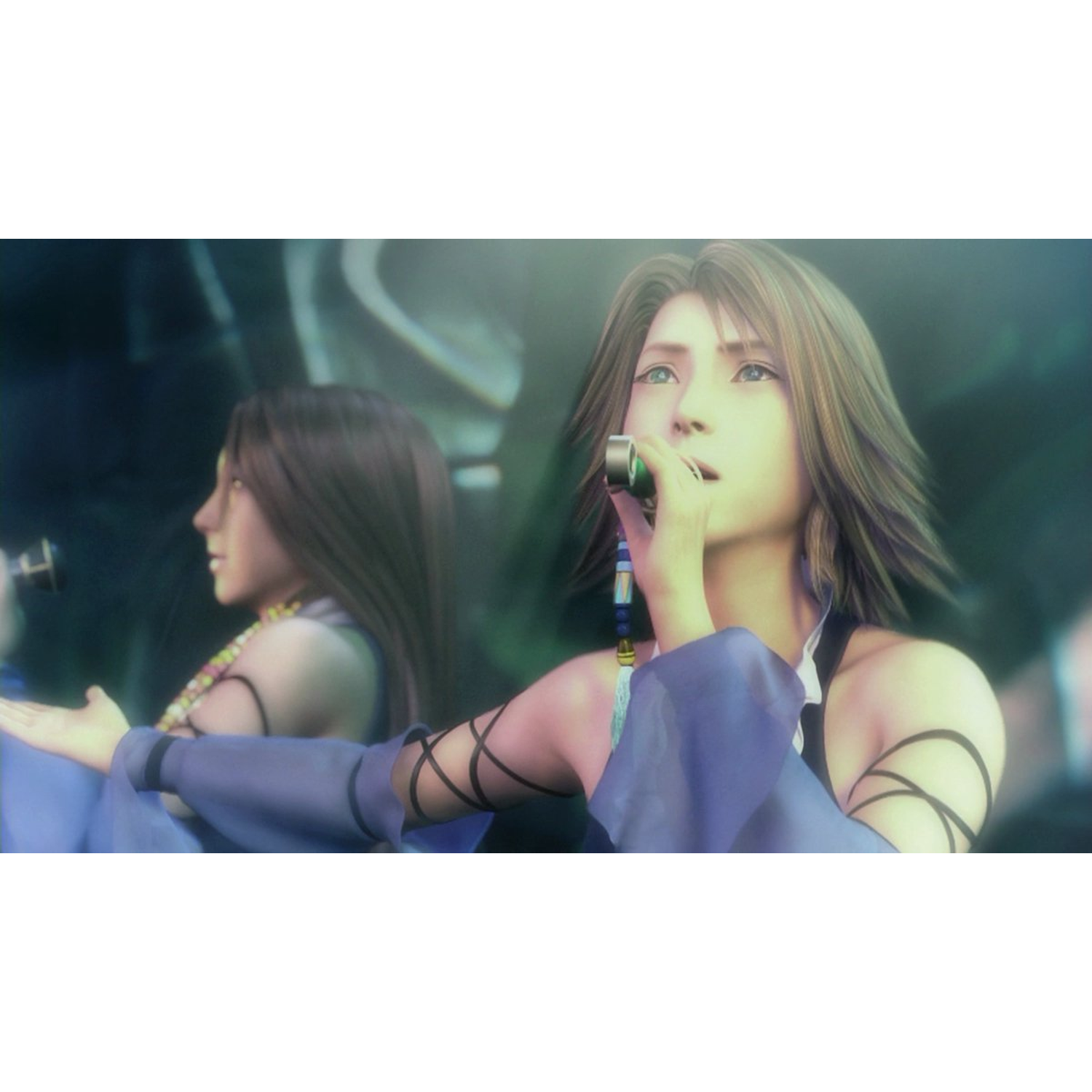 Two women in blue dresses are singing. One holds a microphone. The background is blurred, suggesting a stage or performance setting.