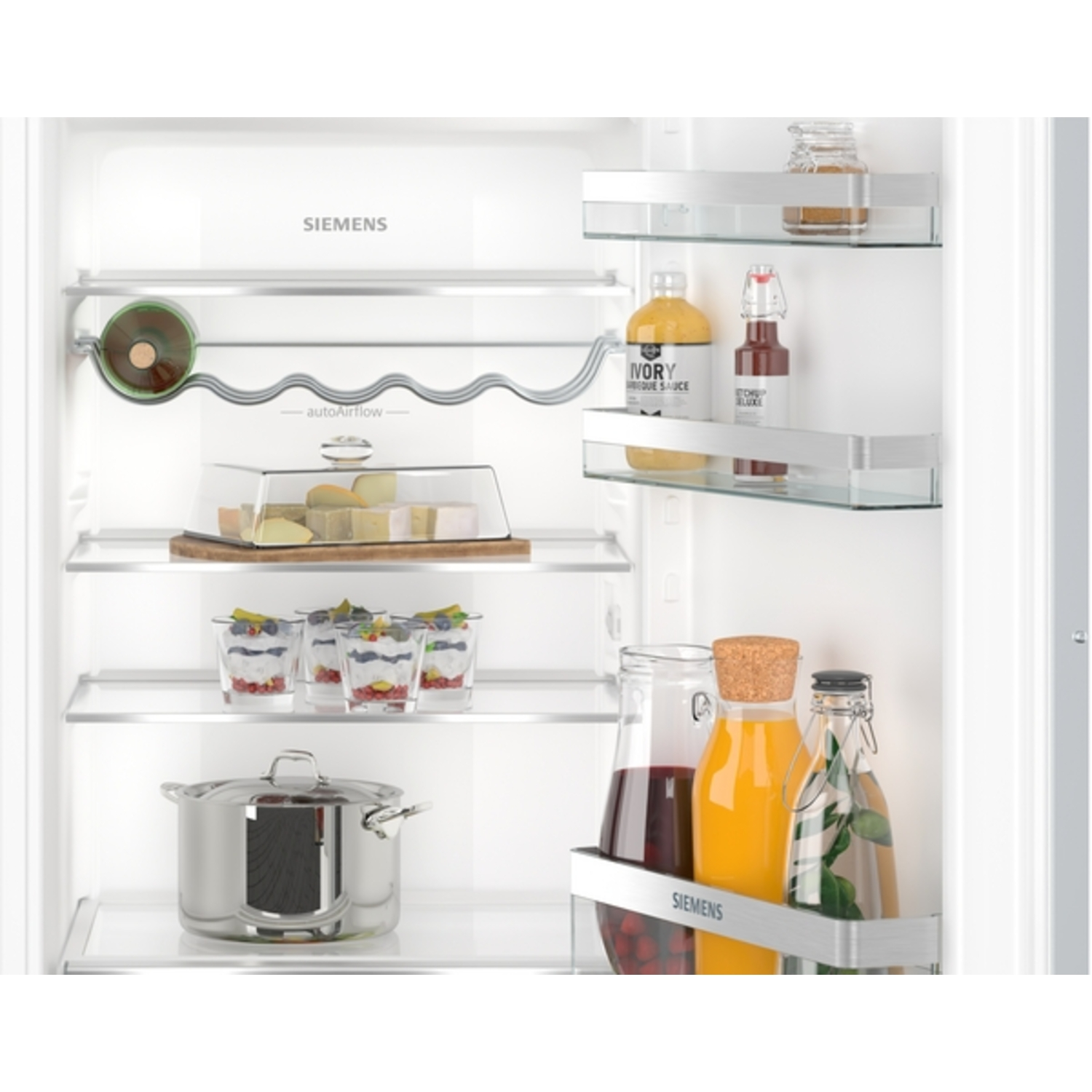 In een Siemens-koelkast zijn verschillende items op planken geplaatst: flessen, potten, desserts, kaas en een pan.