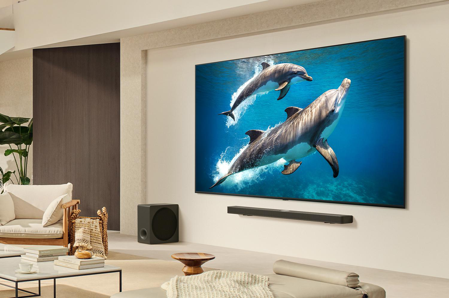 Ein modernes Wohnzimmer mit einem großen Fernseher mit Delphinen im Wasser. Eine Soundbar befindet sich darunter. Möbel sind Sofa und Couchtisch.