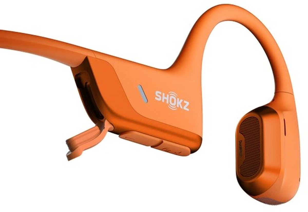 Turuncu Shokz kemik iletimli kulaklık. Marka adı görünür. Tasarım kulağın etrafında kıvrılır.