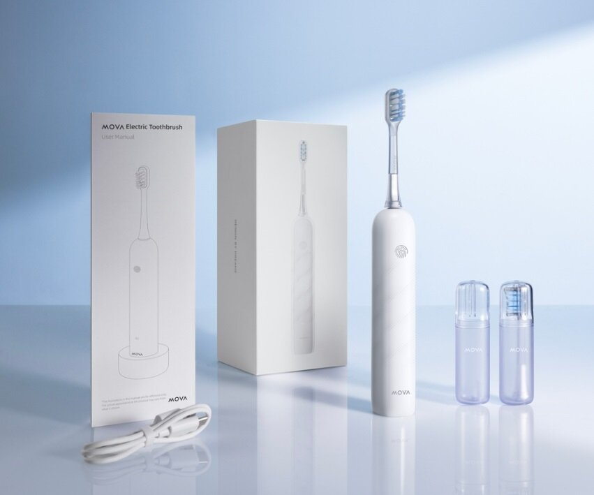 Biała elektryczna szczoteczka do zębów z opakowaniem i akcesoriami. Scena na jasnoniebieskim tle. Szczoteczka do zębów jest punktem centralnym.