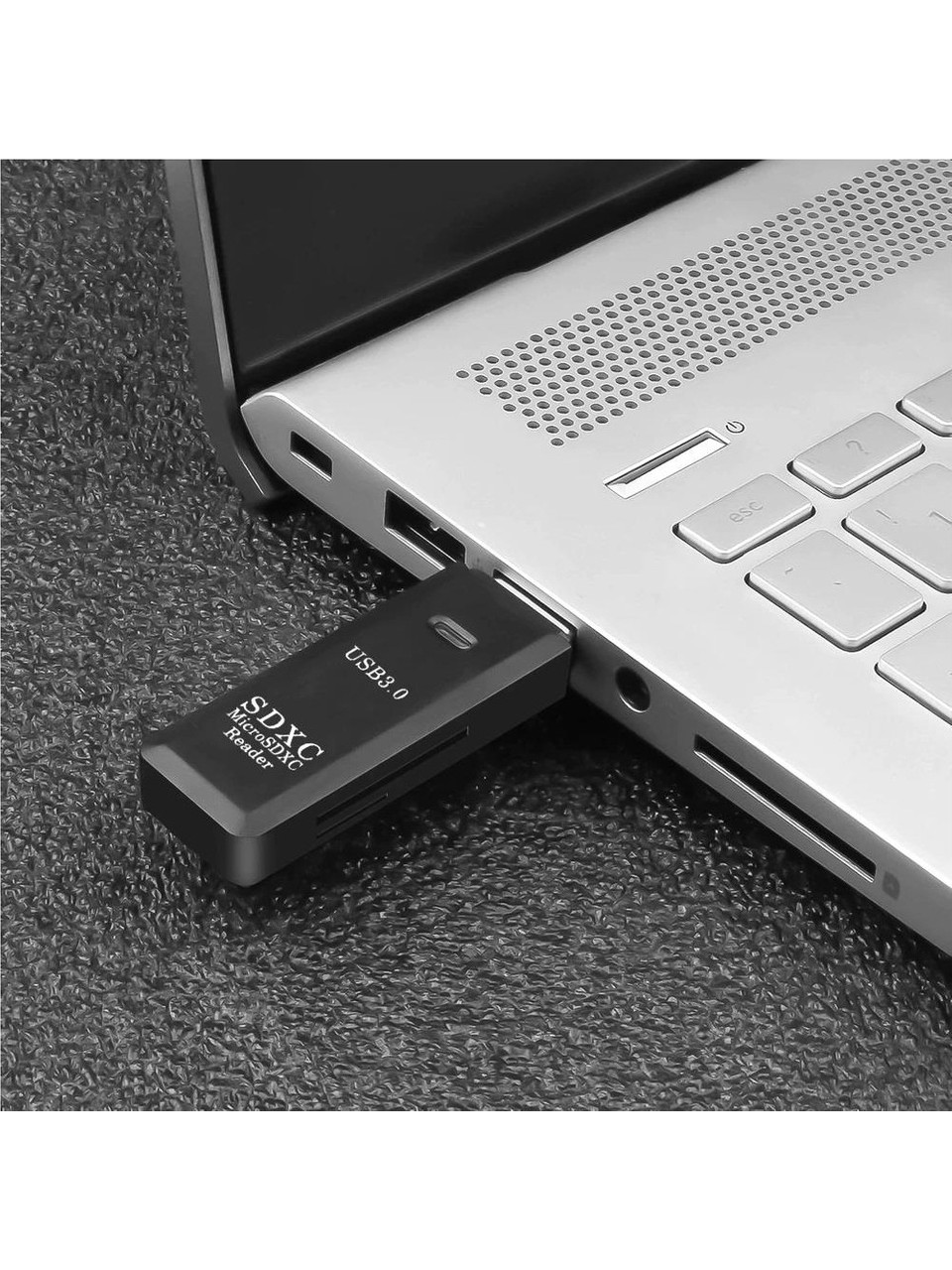 Siyah bir SD kart okuyucu bir dizüstü bilgisayara takılı. Okuyucu üzerinde 'SDXC MicroSDXC Reader USB3.0' yazıyor.