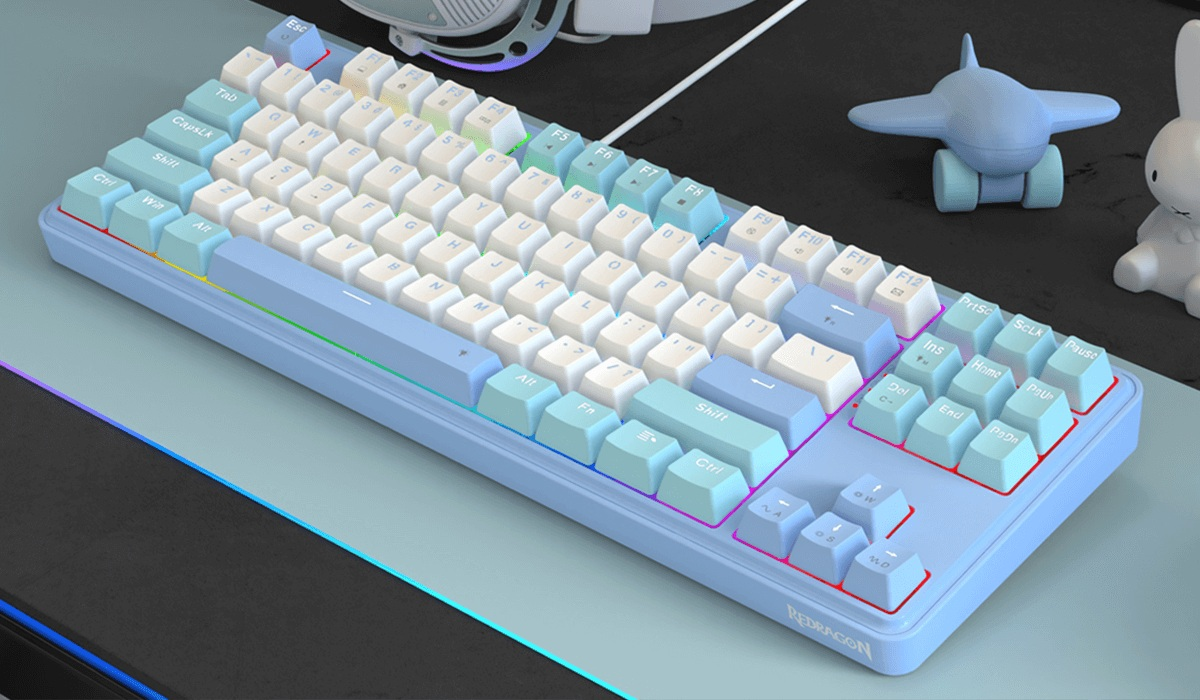 Jasnoniebieska klawiatura mechaniczna z białymi klawiszami i kilkoma kolorowymi klawiszami leży na biurku. Zabawkowy samolot i królik są w tle.