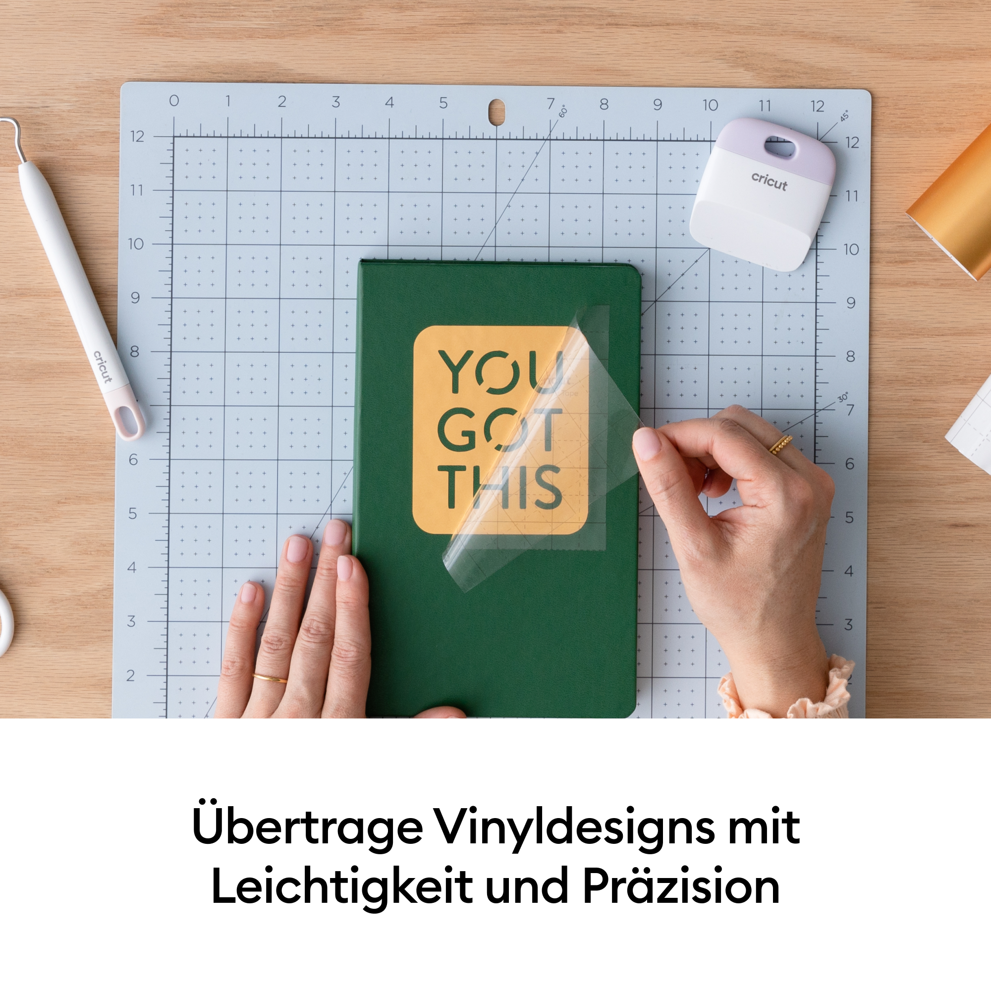 Eine Person bringt einen Vinyl-Aufkleber auf einem grünen Notizbuch auf. Werkzeuge und Zubehör sind sichtbar.
