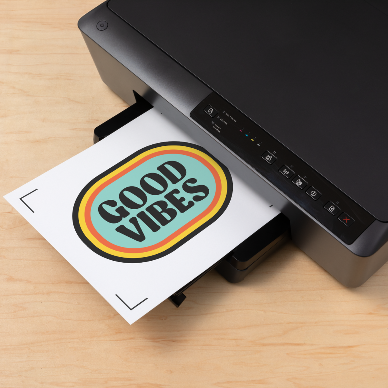 Ein schwarzer Drucker druckt ein Papier mit der Aufschrift 'GOOD VIBES'. Der Drucker steht auf einer hellen Holzoberfläche.