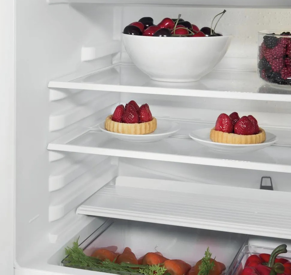W lodówce na półkach znajdują się wiśnie, jagody i tarty truskawkowe. Marchew i papryka w dolnej szufladzie.