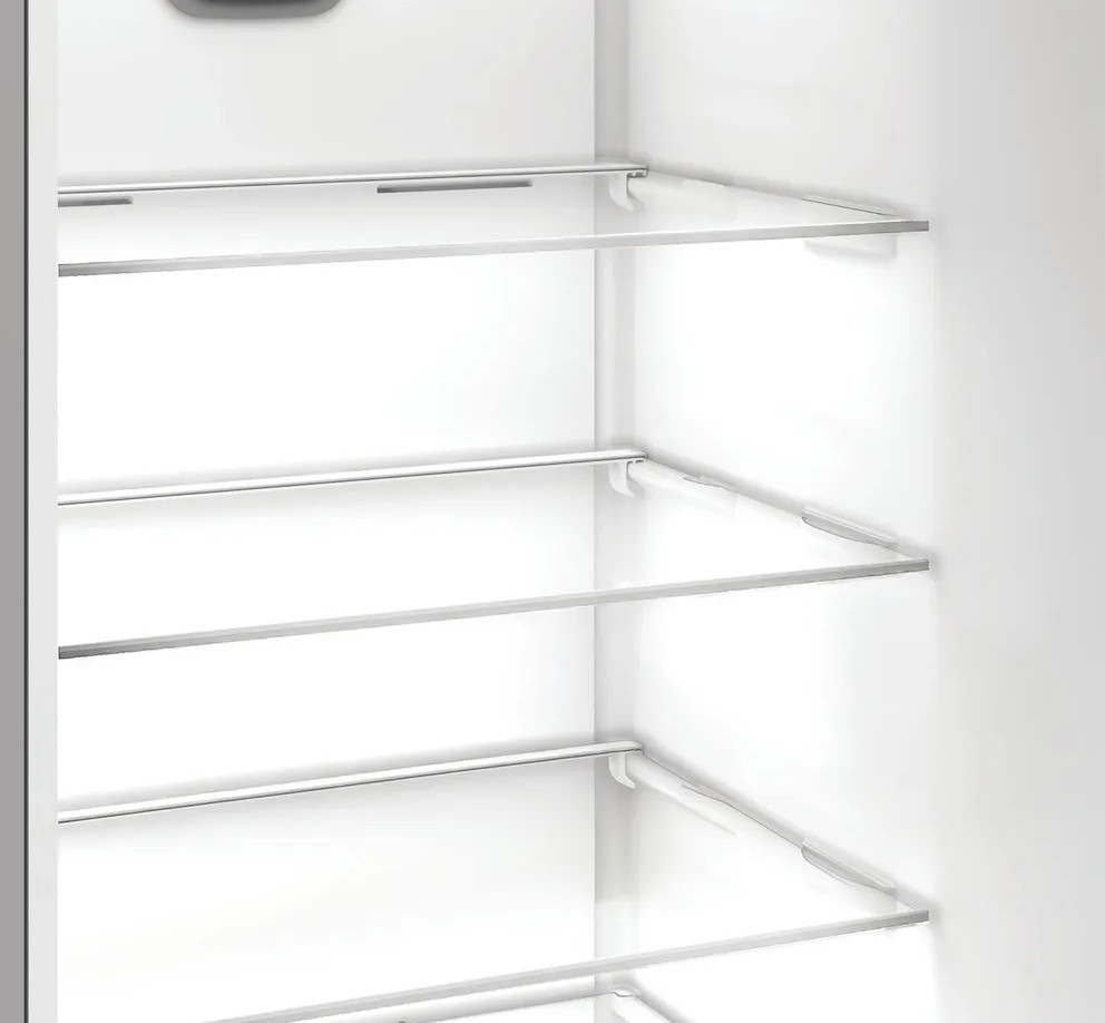 Puste wnętrze białej lodówki. Szklane półki wsparte na białych wspornikach. Scena jest czysta i dobrze oświetlona, bez żadnych przedmiotów.