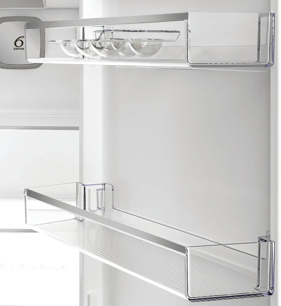 Wewnątrz lodówki widoczne są przezroczyste półki i małe miseczki. Logo 6th sense znajduje się z boku. Tło jest białe.
