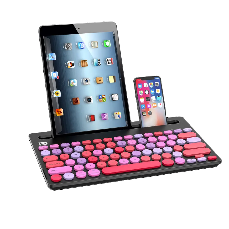 Yuvarlak pembe ve mor tuşlu siyah bir klavye. Arkada bir iPad ve bir telefon duruyor. Beyaz zemin.