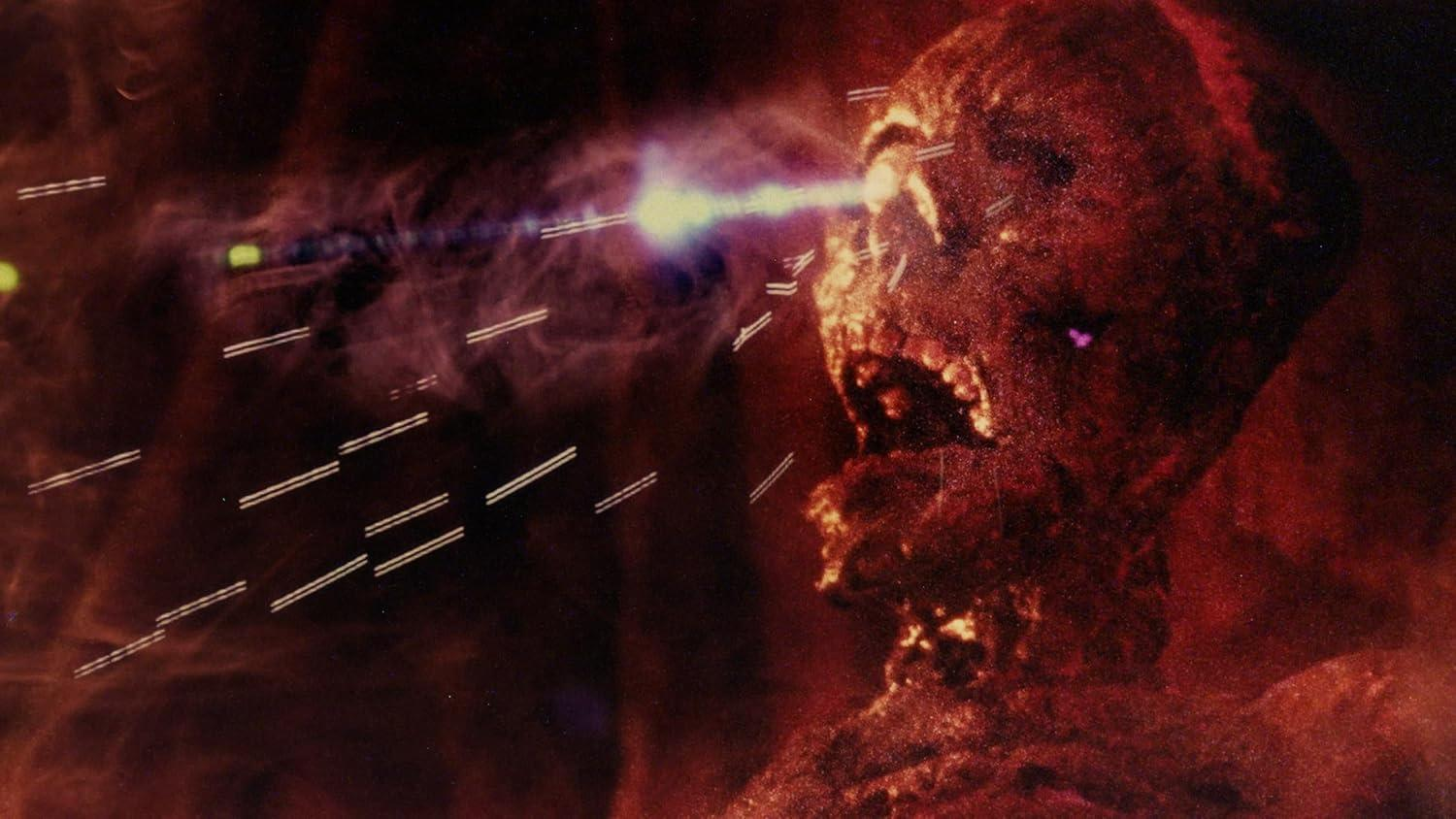 Eine feurige Figur mit offenem Mund wird von einem Lichtstrahl getroffen. Der Hintergrund ist ein dunkler, rötlicher Nebel mit weißen Linien.