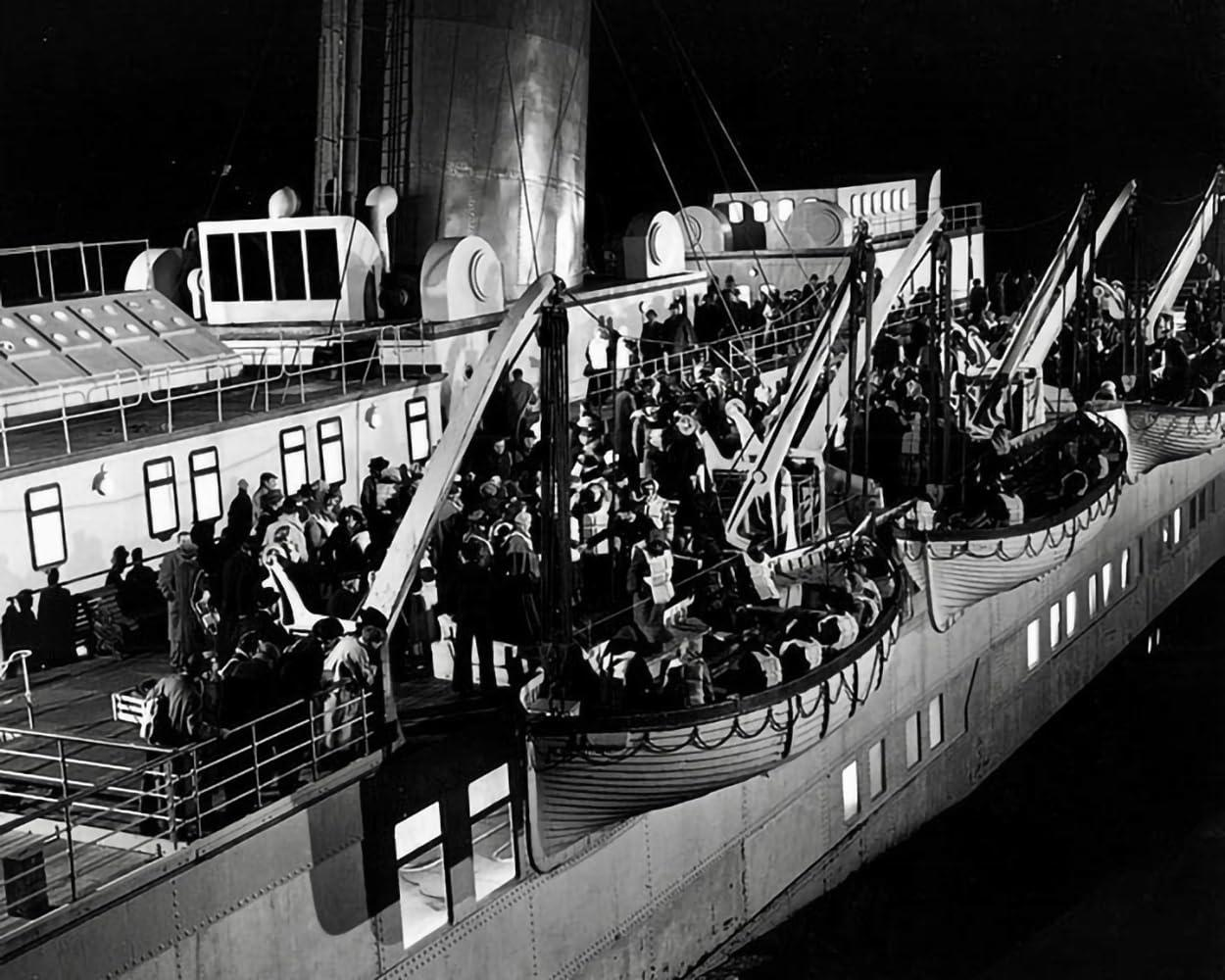 Menschen an Bord eines Schiffes bei Nacht. Rettungsboote werden heruntergelassen. Passagiere drängen sich an Deck und in den Booten.