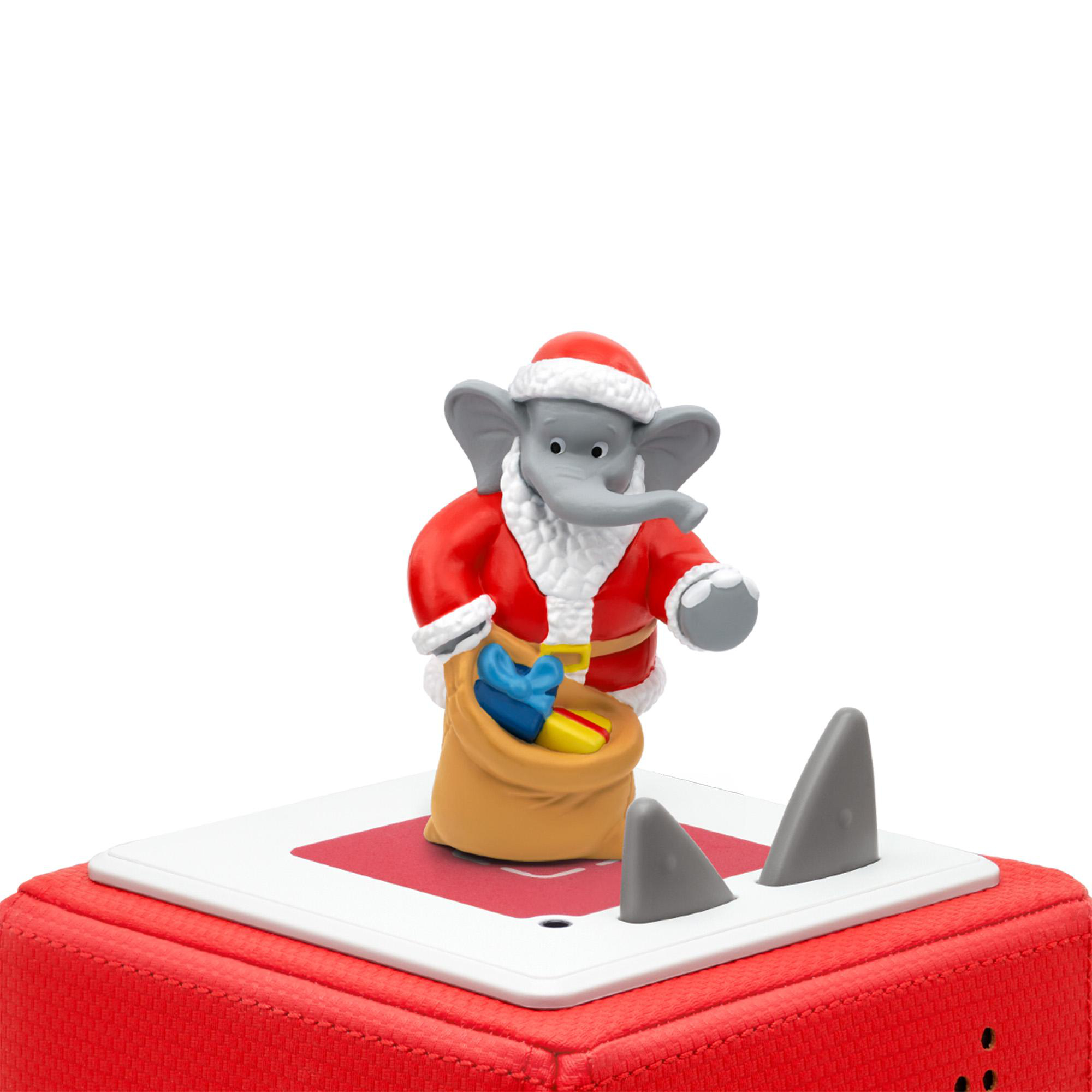 Ein Elefant im Weihnachtsmann-Anzug hält eine Geschenktüte auf einer rot-weißen Plattform mit Haifischflossenformen.