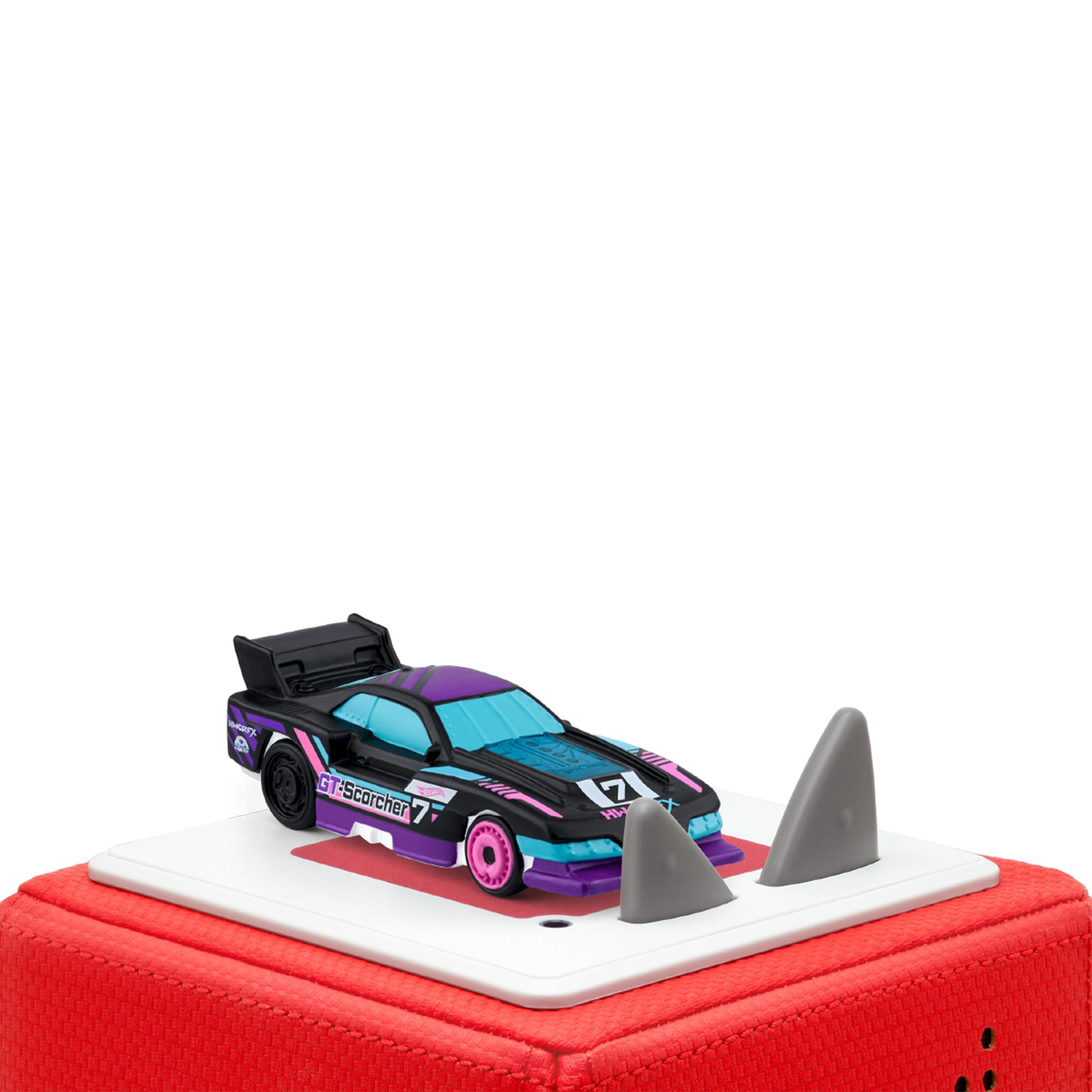 Ein Spielzeugauto mit schwarzen, lila und rosa Akzenten steht auf einer weißen Plattform mit zwei Haifischflossen. Die Plattform befindet sich auf einem roten Würfel.