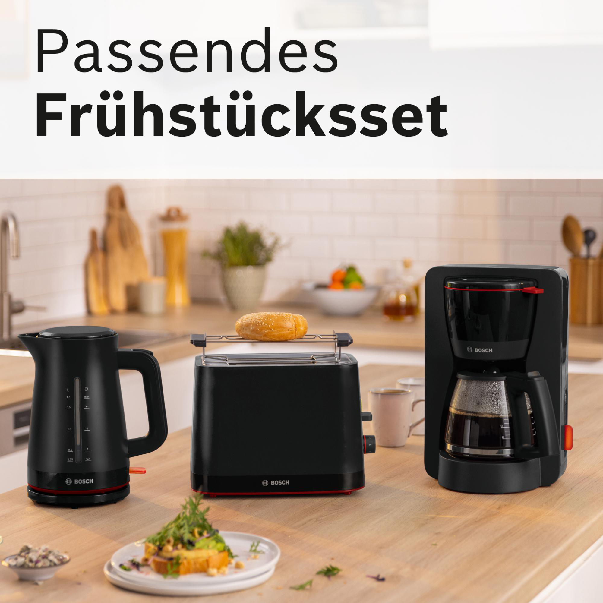 Frühstücks-Set: Wasserkocher, Toaster mit Brot, Kaffeemaschine. Alles schwarz, mit Holzoberfläche. Text: 'Passendes Frühstücksset'.