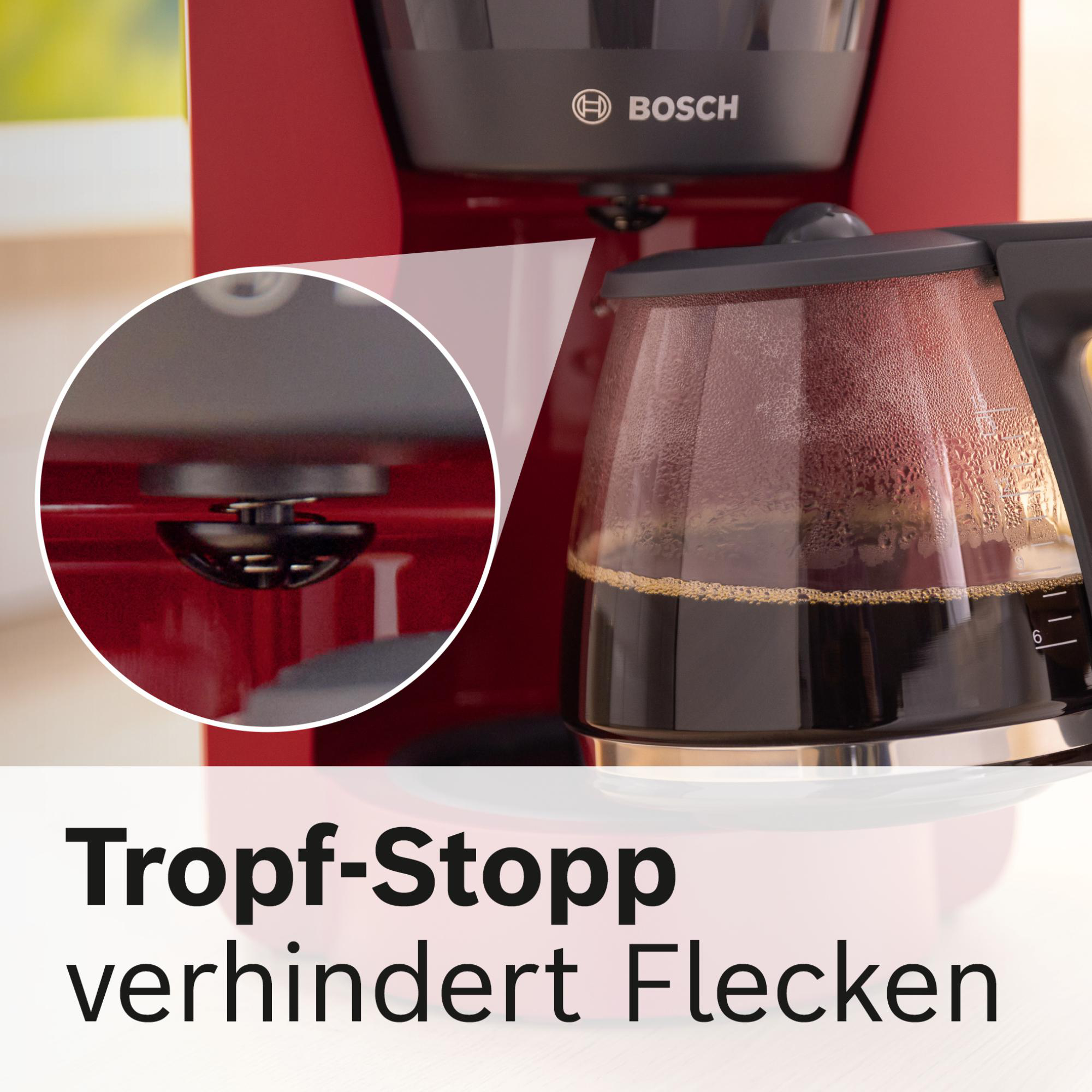 Ein roter Bosch-Kaffeeautomat mit einer Glaskaraffe, die mit Kaffee gefüllt ist. Text sagt 'Tropf-Stopp verhindert Flecken'.