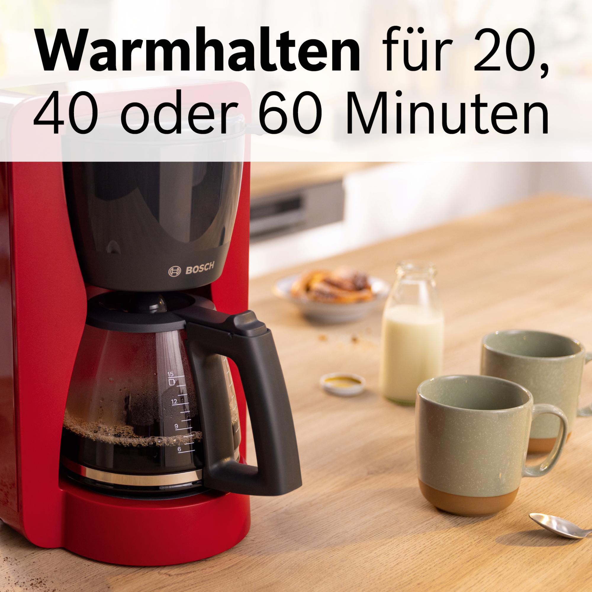 Roter Kaffeemaschine mit Kaffee, Tassen und Milch auf einem Holztisch. Text: Warmhalten für 20, 40 oder 60 Minuten.