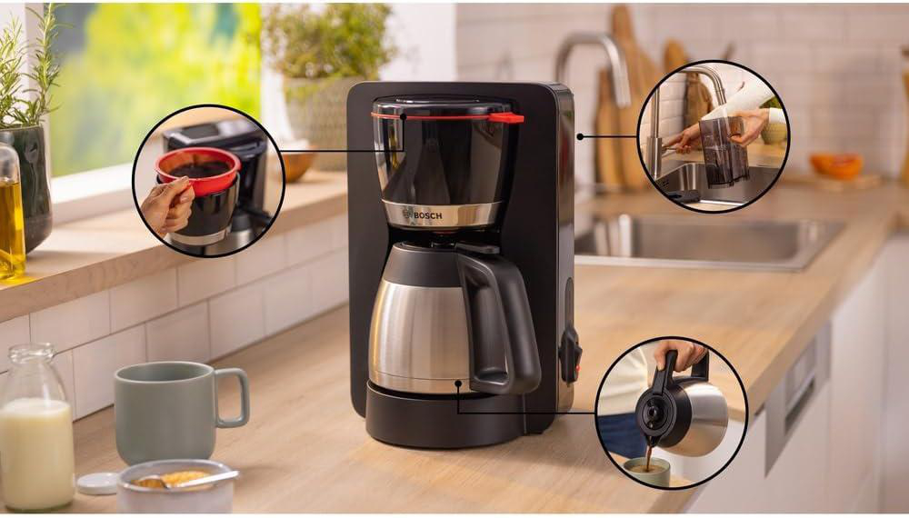 Eine Kaffeemaschine mit rotem Akzent. Sie zeigt den Brühvorgang, vom Hinzufügen von Kaffeepulver bis zum Eingießen in eine Tasse. Küche im Hintergrund.