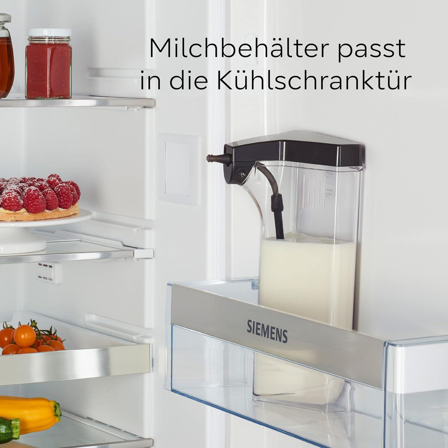 Im Kühlschrank ein Milchbehälter mit schwarzem Deckel. Himbeerkuchen, Tomaten und Zucchini auf Regalen.