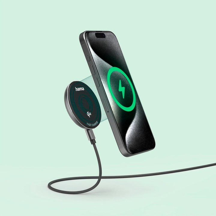 Smartfon ładuje się bezprzewodowo, wyświetlając zielony symbol ładowania. Magnetyczna podkładka ładująca, oznaczona 'hama', jest połączona kablem.