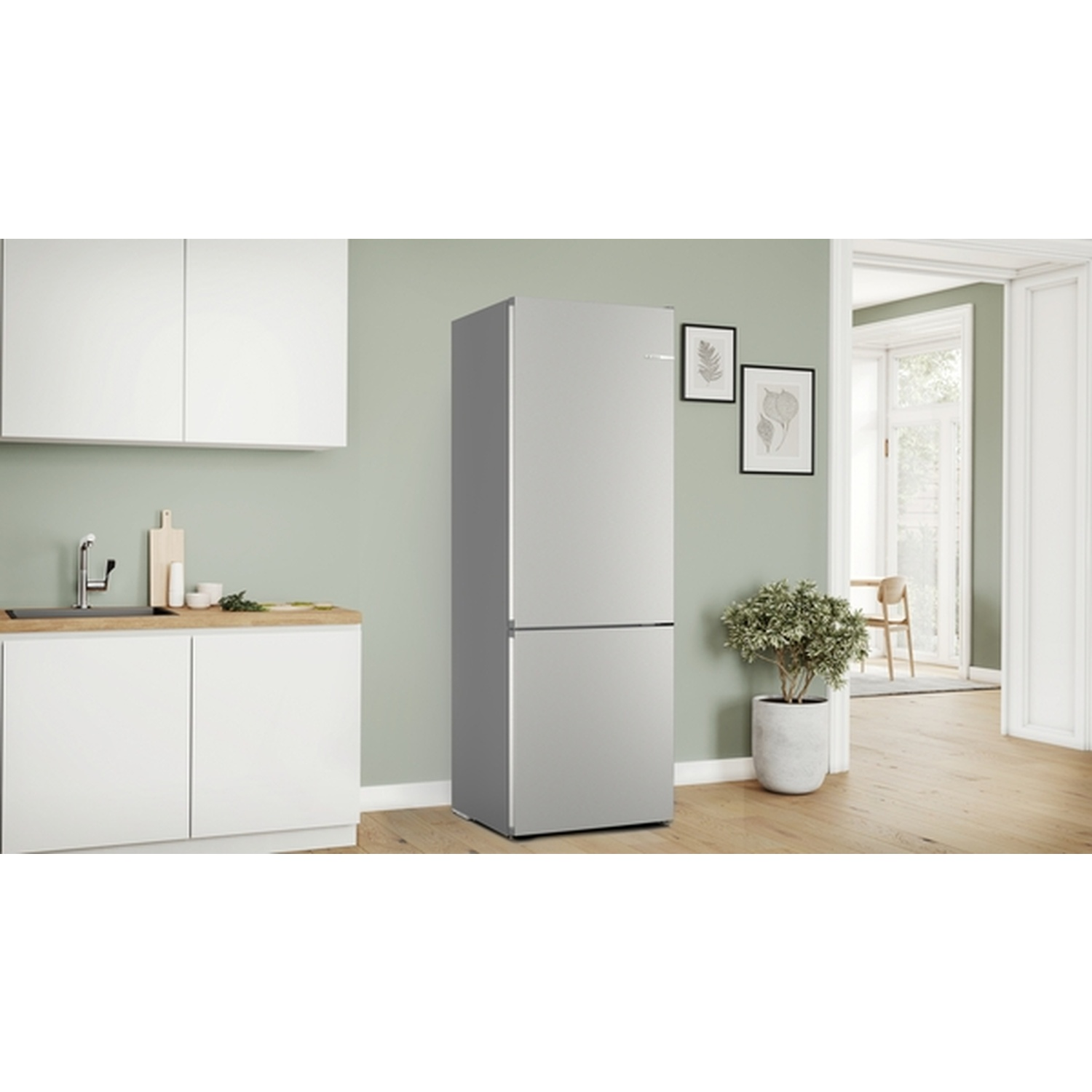 A silver refrigerator stands in a kitchen. White cabinets, a wooden countertop, and a potted plant are also visible.