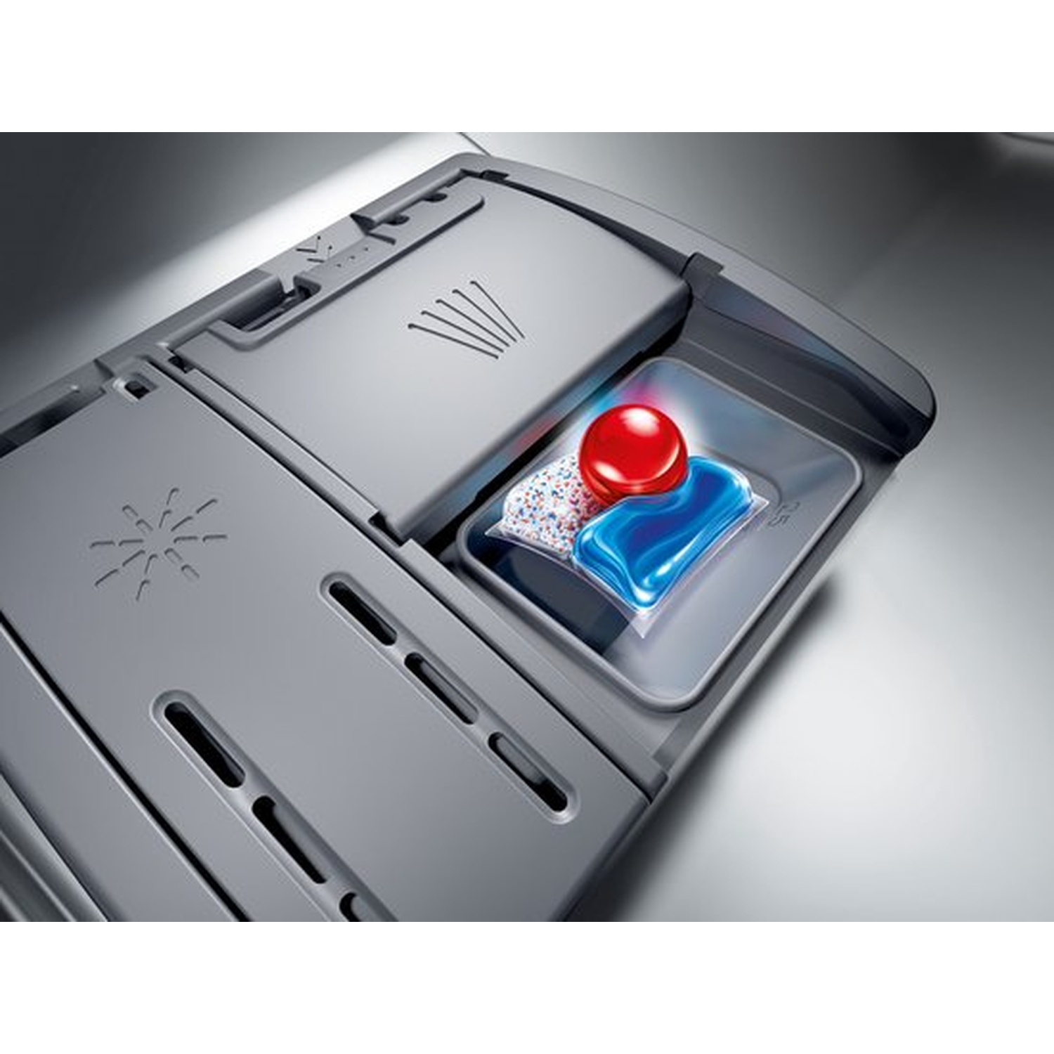 Distributeur de détergent pour lave-vaisselle. Une tablette rouge, du gel bleu et des granulés blancs sont à l'intérieur. Compartiment gris avec soleil.