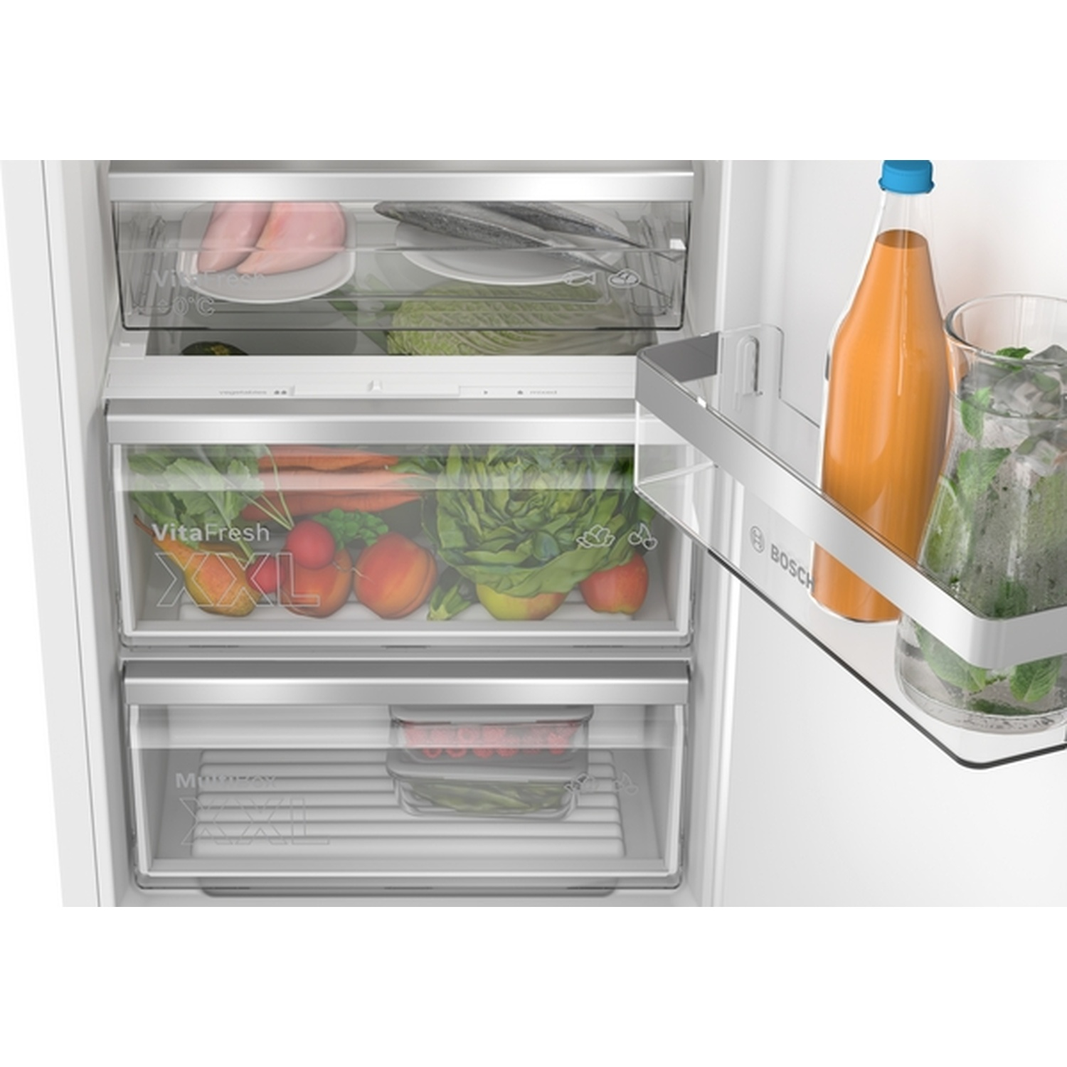 Intérieur de réfrigérateur montrant des produits frais et une bouteille de jus. Légumes dans les tiroirs. Poisson et poulet également visibles.