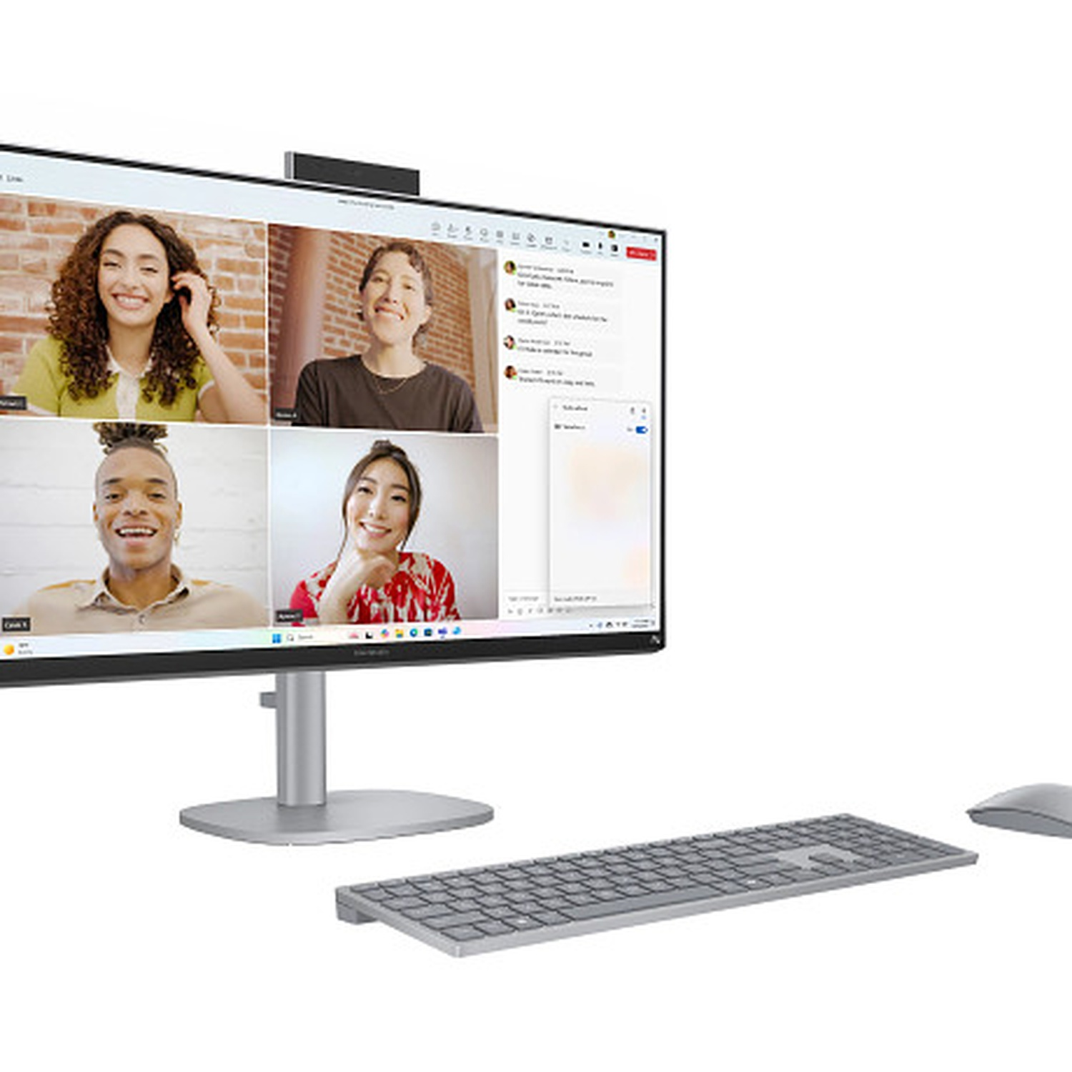 Moniteur affichant un appel vidéo avec quatre participants. Clavier, souris et pied de moniteur au premier plan. Fond blanc.