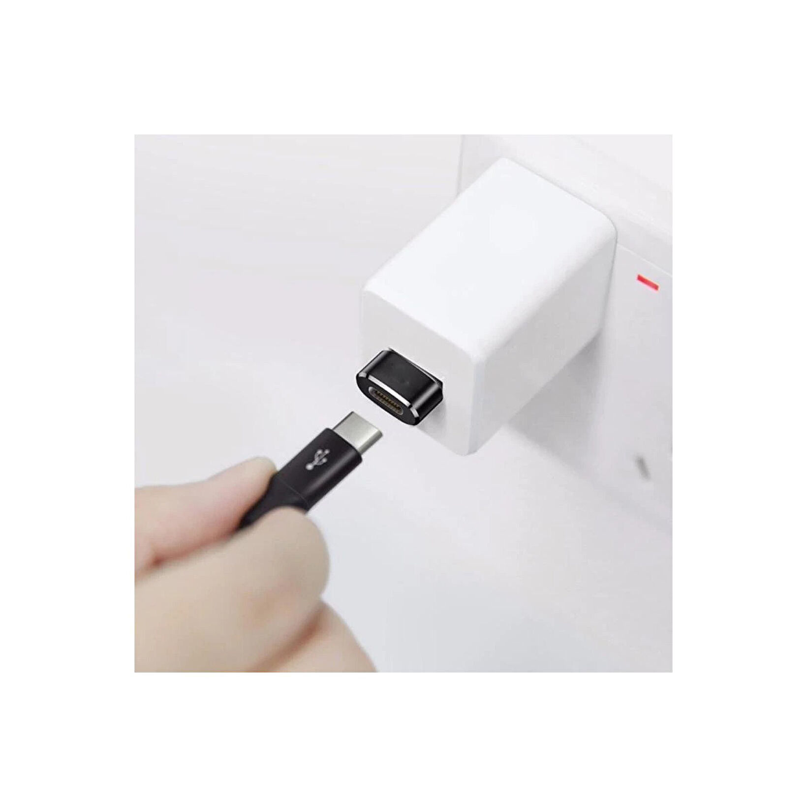 El, siyah bir USB-C kablosunu tutuyor, beyaz bir şarj cihazına takıyor. Şarj cihazı beyaz bir duvar prizine takılı.