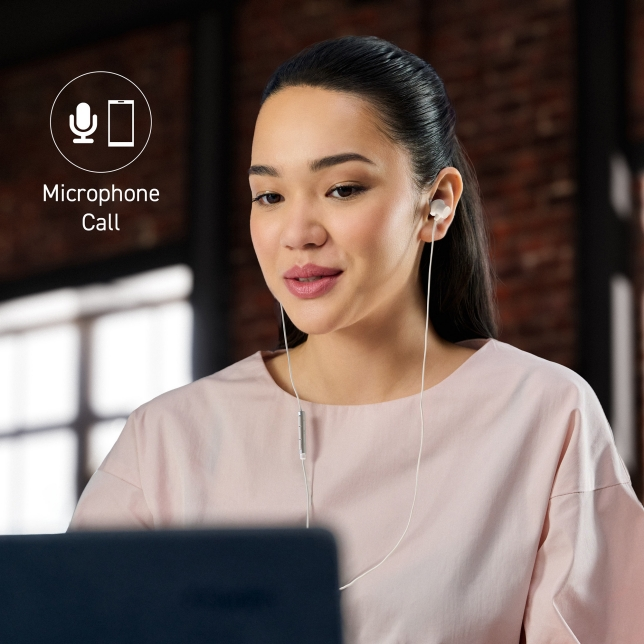 Kobieta w słuchawkach, korzystająca z laptopa i uczestnicząca w połączeniu. Patrzy na ekran z ikoną połączenia mikrofonowego nad głową.