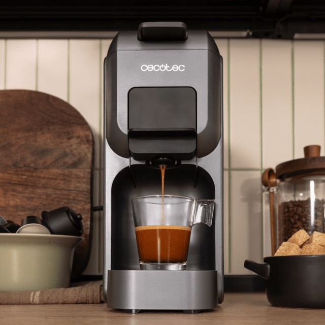 Ekspres do kawy dozujący kawę do szklanki. Inne elementy to drewniana deska do krojenia, kostki cukru i ziarna kawy.