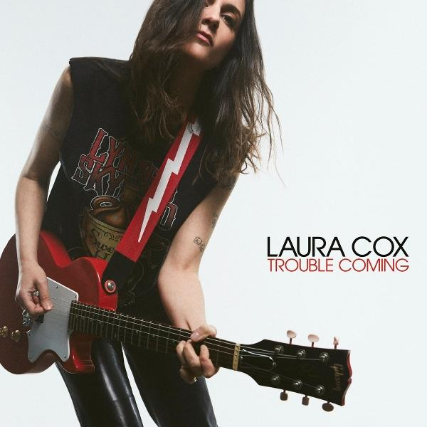 Frau mit roter Gitarre, schwarzes Shirt mit Blitzgurt. Text: Laura Cox, Trouble Coming.