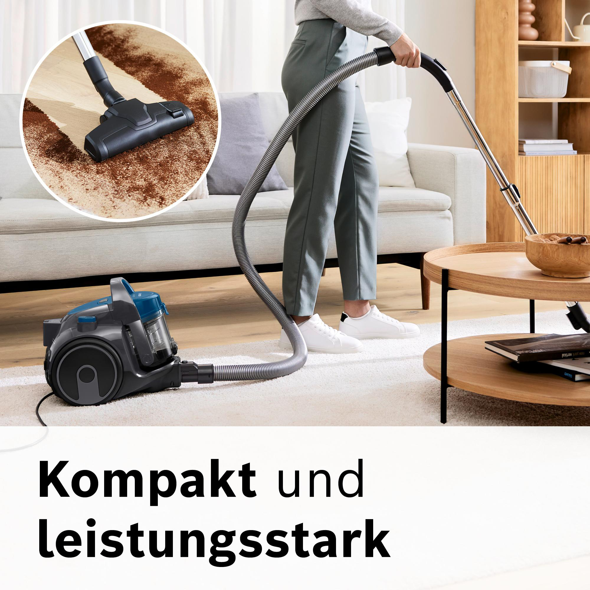 Eine Person saugt einen weißen Teppich. Ein Staubsauger befindet sich im Vordergrund, Sofa und Tisch im Hintergrund.