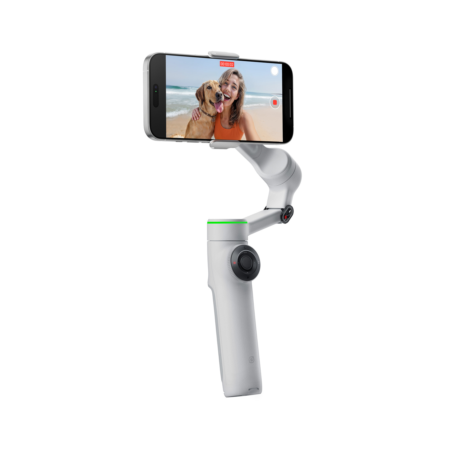 A white gimbal holds a phone showing a woman and dog on a beach. The gimbal has a green light and a dial. White background.