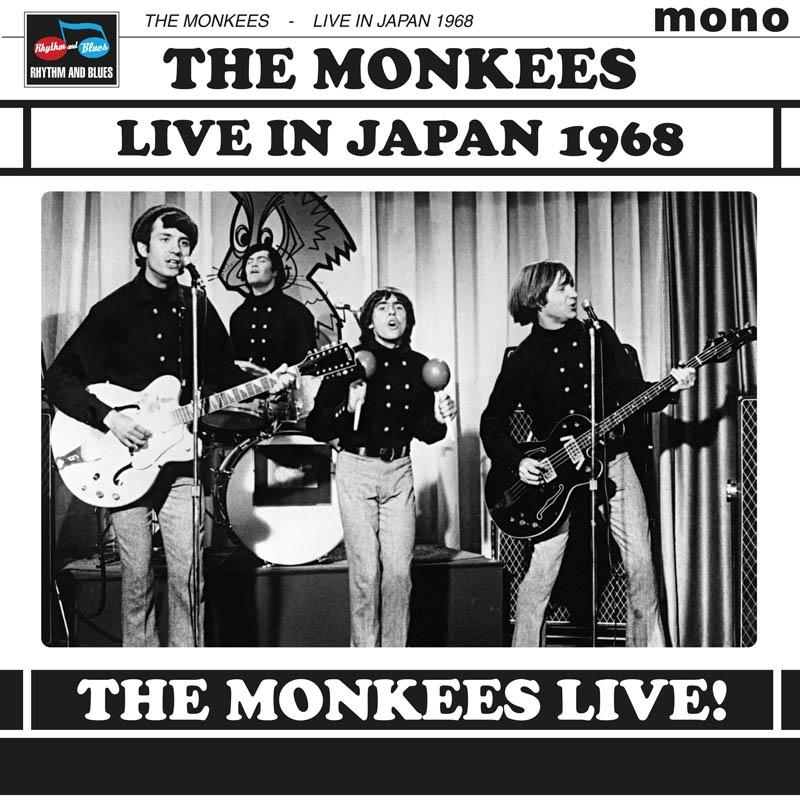A The Monkees zenekar 1968-ban Japánban koncertezett. Négy fekete inges férfi gitáron, dobon és maracason játszik a színpadon.