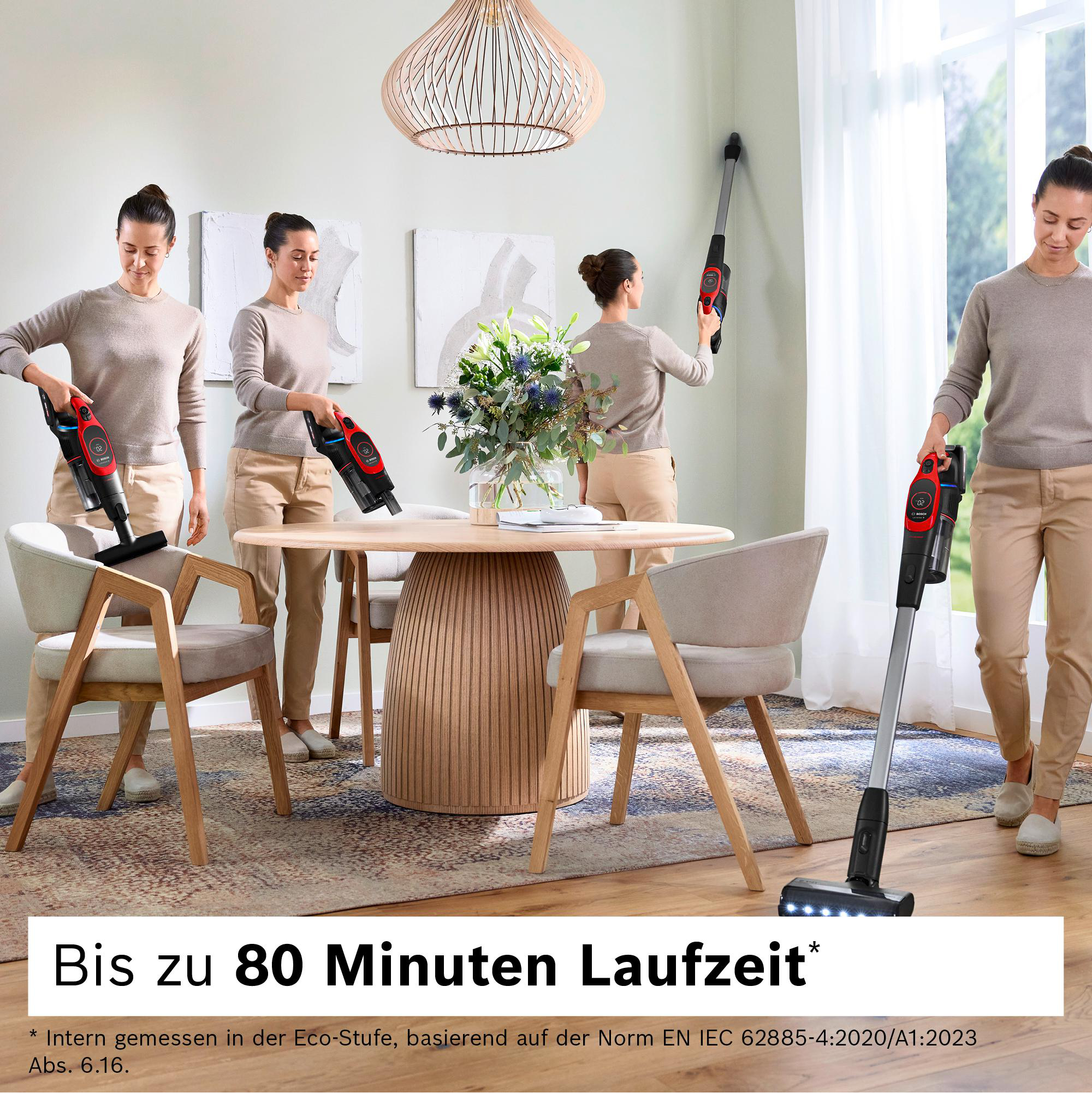 Eine Frau benutzt einen rot-schwarzen Staubsauger in einem Raum. Der Raum hat einen Tisch, Stühle und einen Teppich. Im Hintergrund ist ein Fenster.