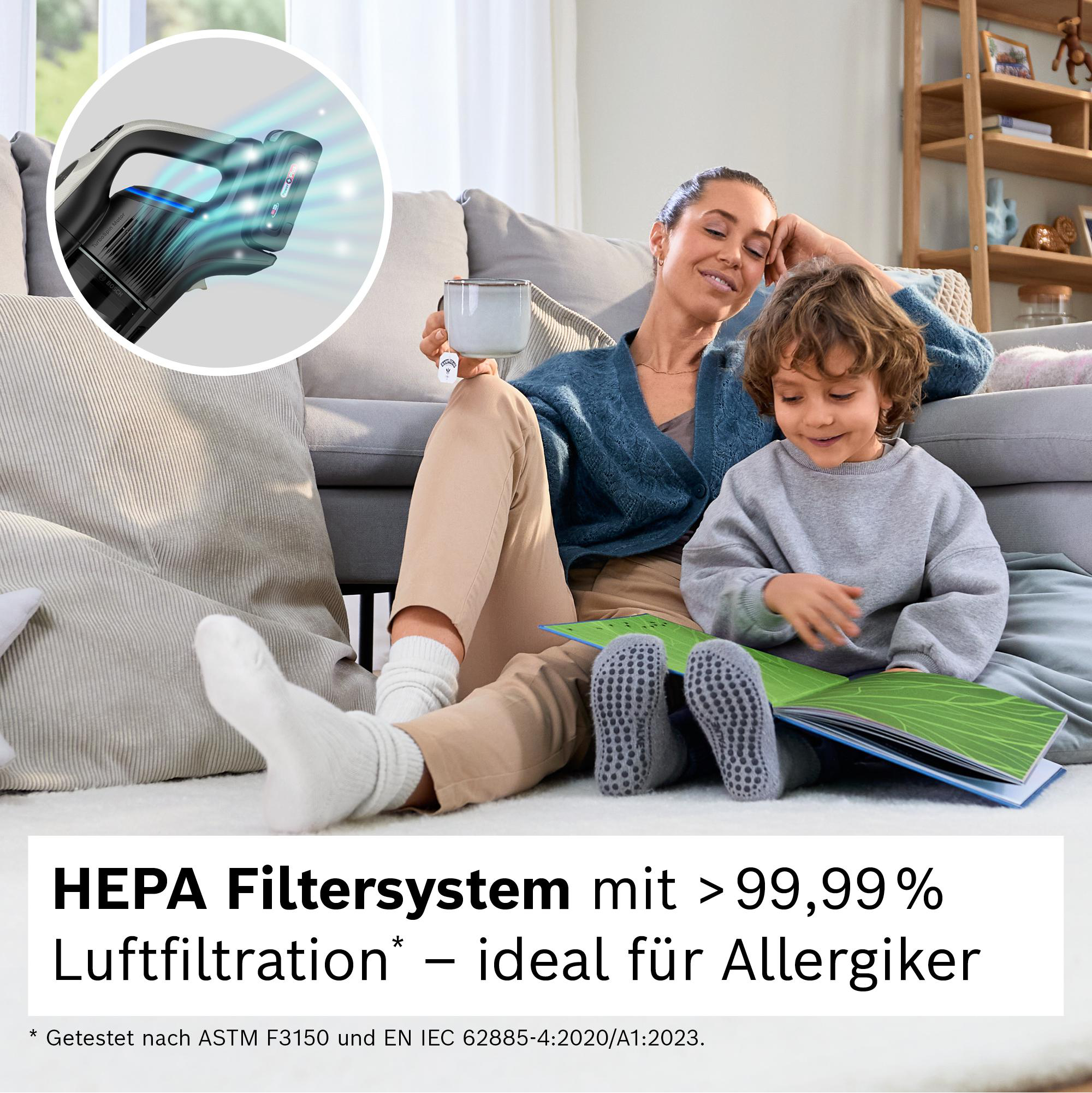 Eine Frau und ein Kind sitzen auf einem Sofa. Ein Staubsauger wird angezeigt. Text: HEPA-Filtersystem mit <gt/>99,99 % Luftfiltration – ideal für Allergiker.