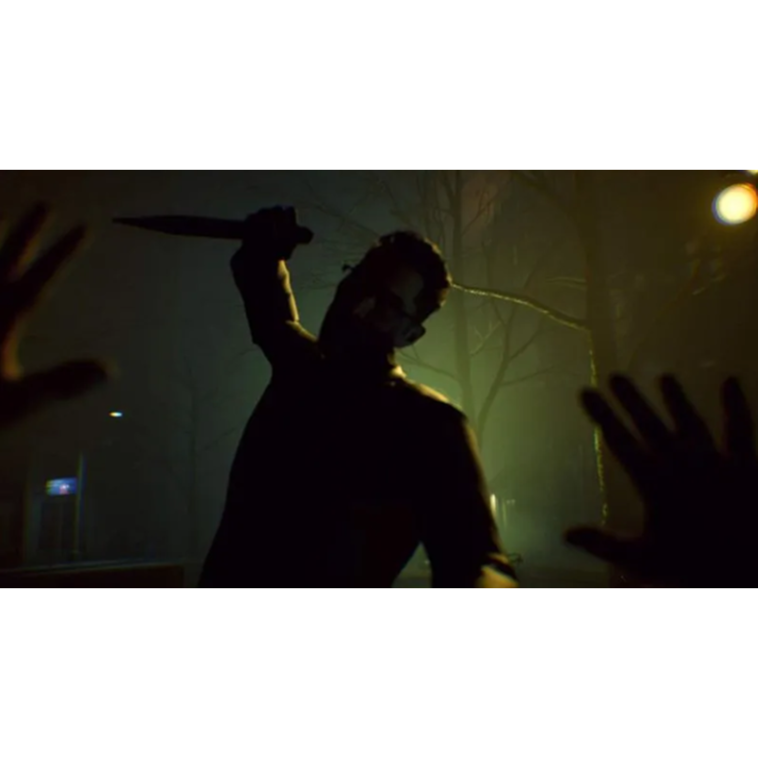 A silhouetted figure raises a knife in a dim, foggy environment. Hands reach out in front. Bare trees and a street lamp are visible.