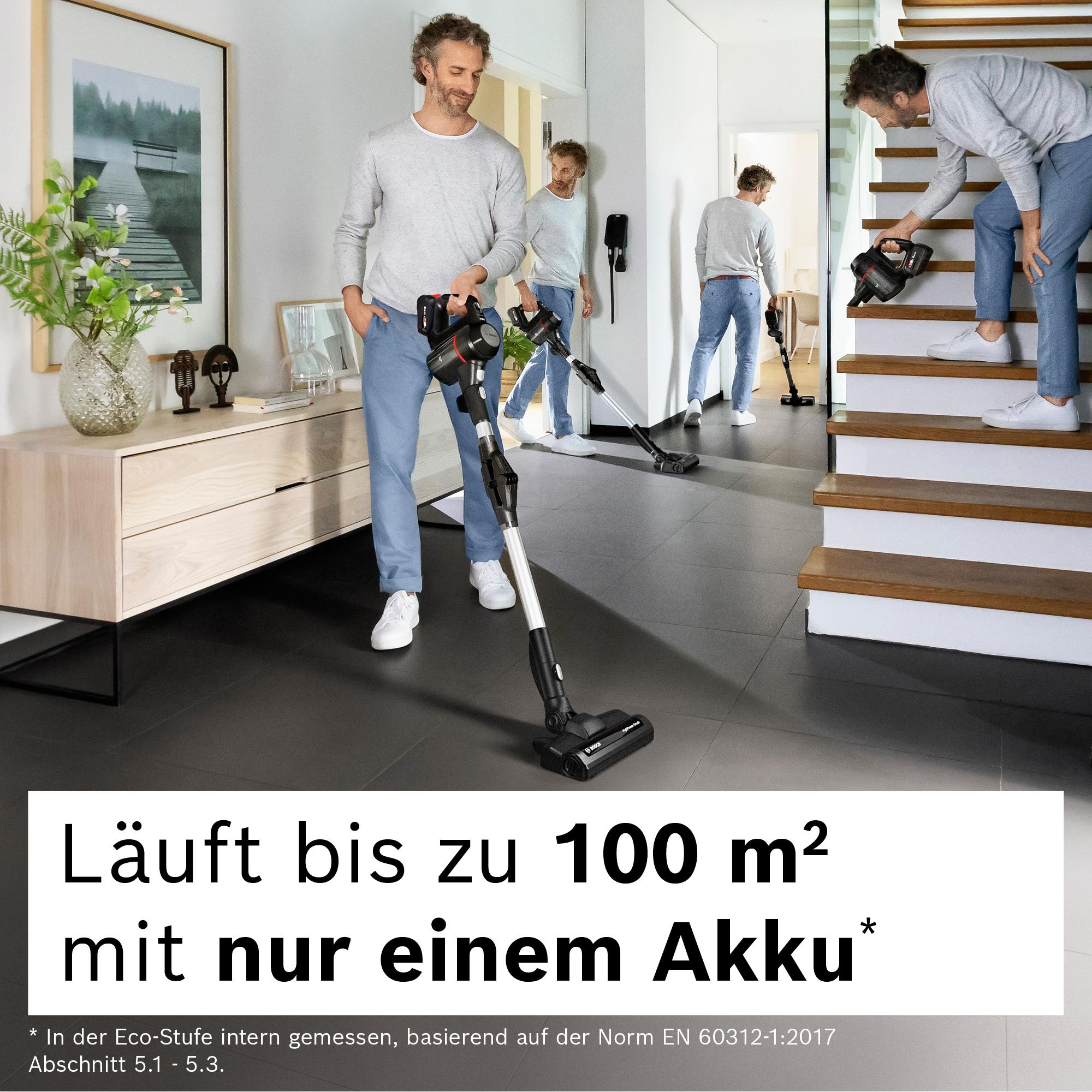 Ein Mann benutzt einen Staubsauger. Andere sind im Hintergrund, einer geht die Treppe hoch. Text: 100 m² mit einem Akku.