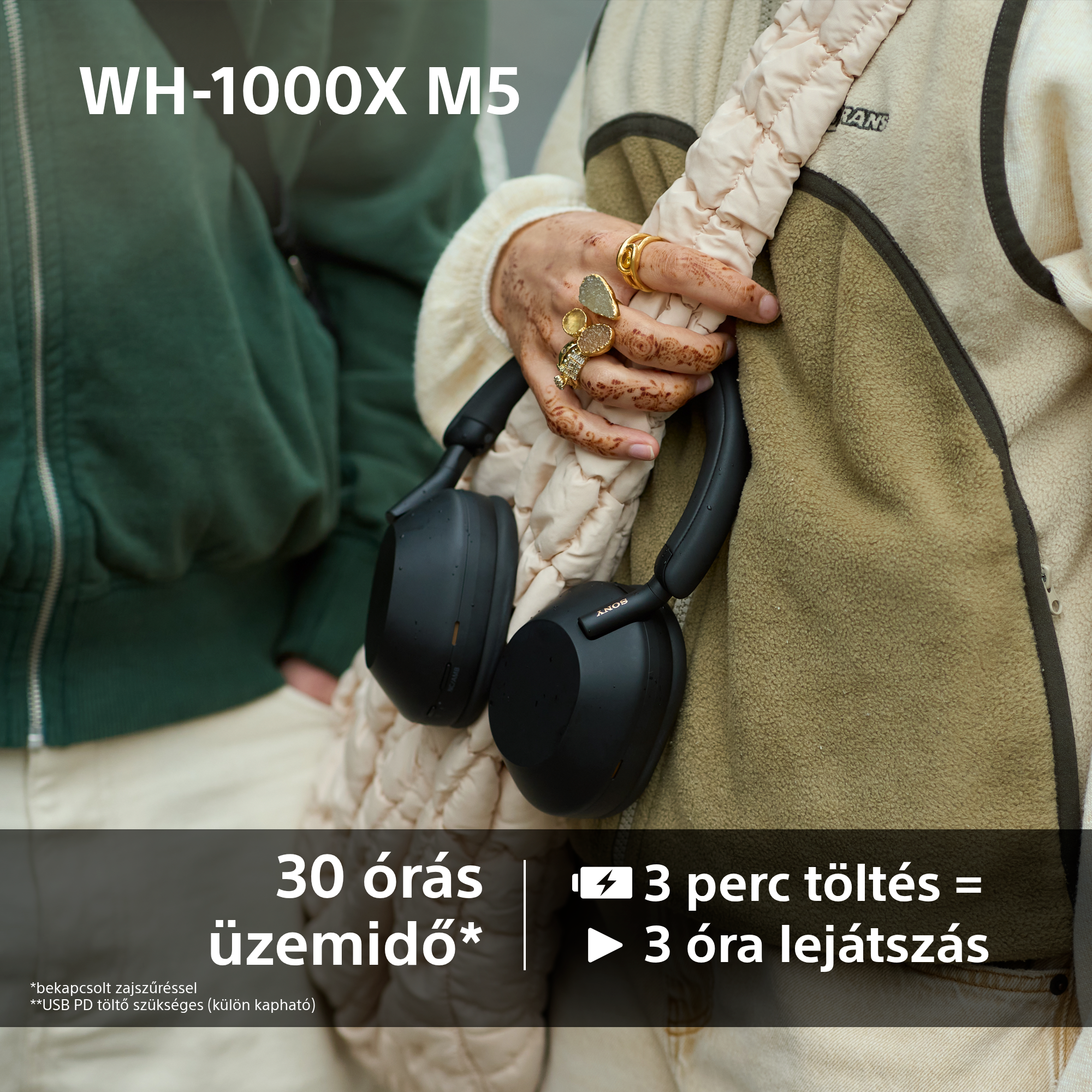 Egy személy fekete Sony fejhallgatót tart. A személy kabátot visel, és gyűrűk vannak az ujjain.