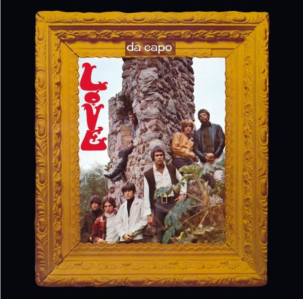 Albumcover: Band Love, goldgerahmt, vor einer Steinmauer. Das Wort "Love" ist prominent. Mehrere Bandmitglieder sind sichtbar.