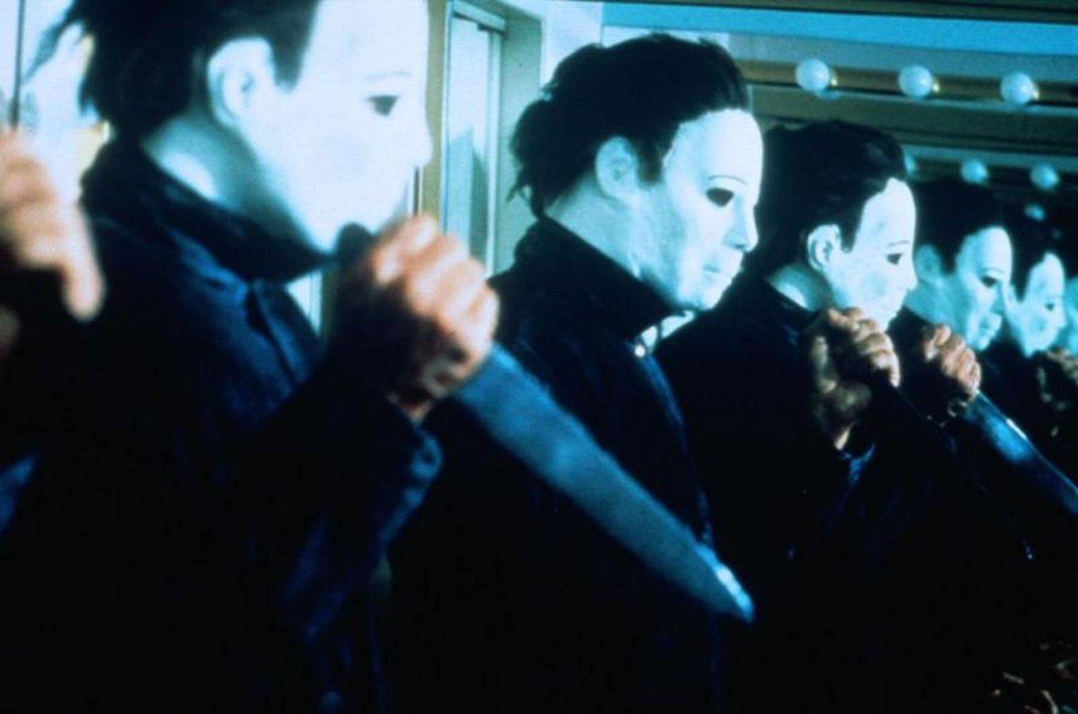Reihe von Figuren mit weißen Masken und schwarzen Outfits, die Messer halten, wahrscheinlich eine Halloween-Szene. Spiegel erzeugen einen visuellen Effekt.