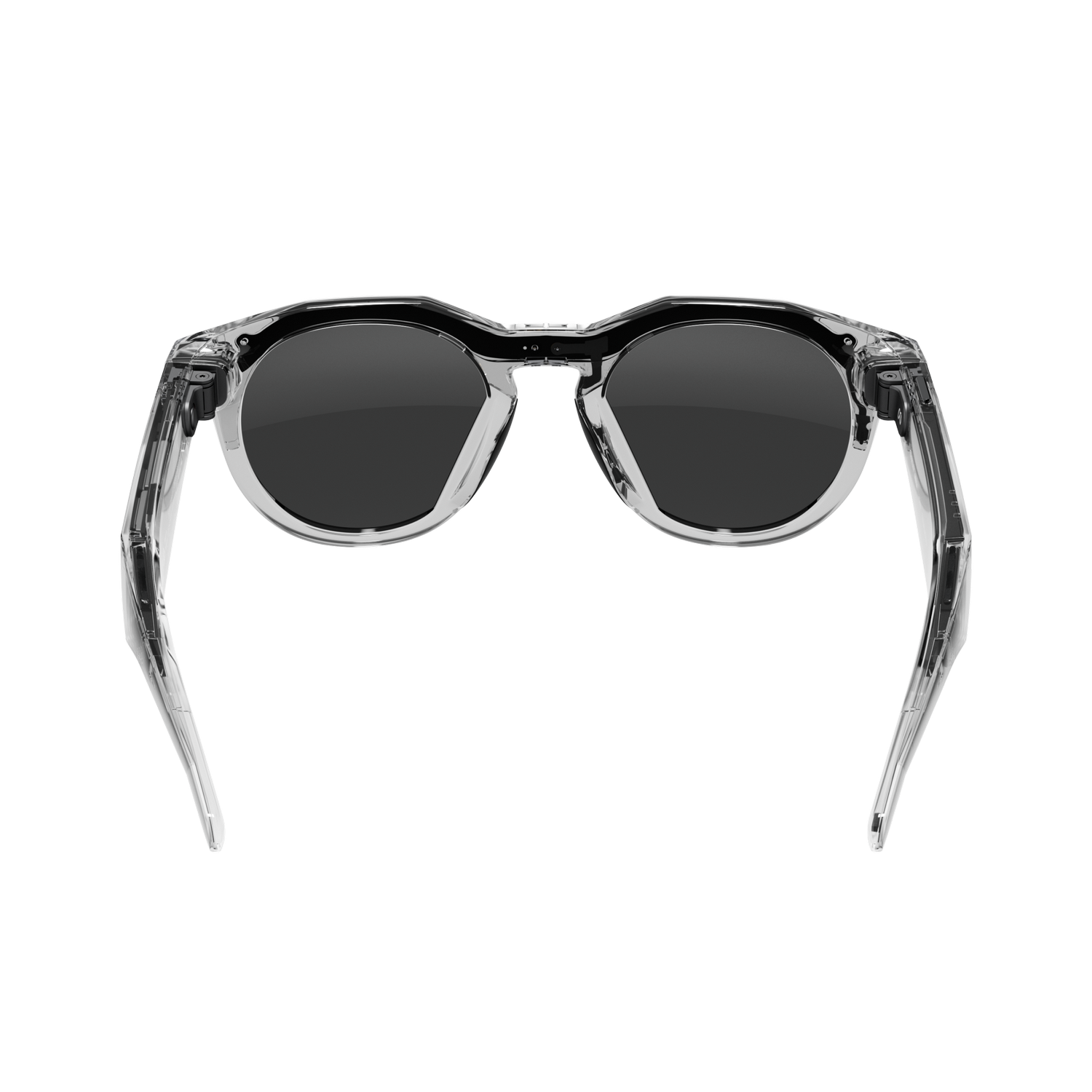 Gafas de sol transparentes con lentes oscuras centradas sobre fondo gris. Patillas abiertas. Marco con borde superior negro.
