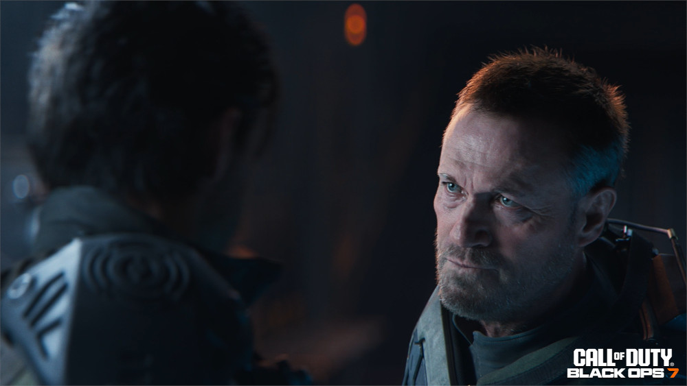 Close up of two men looking at each other. One man is in focus, older with a beard. The other is out of focus.